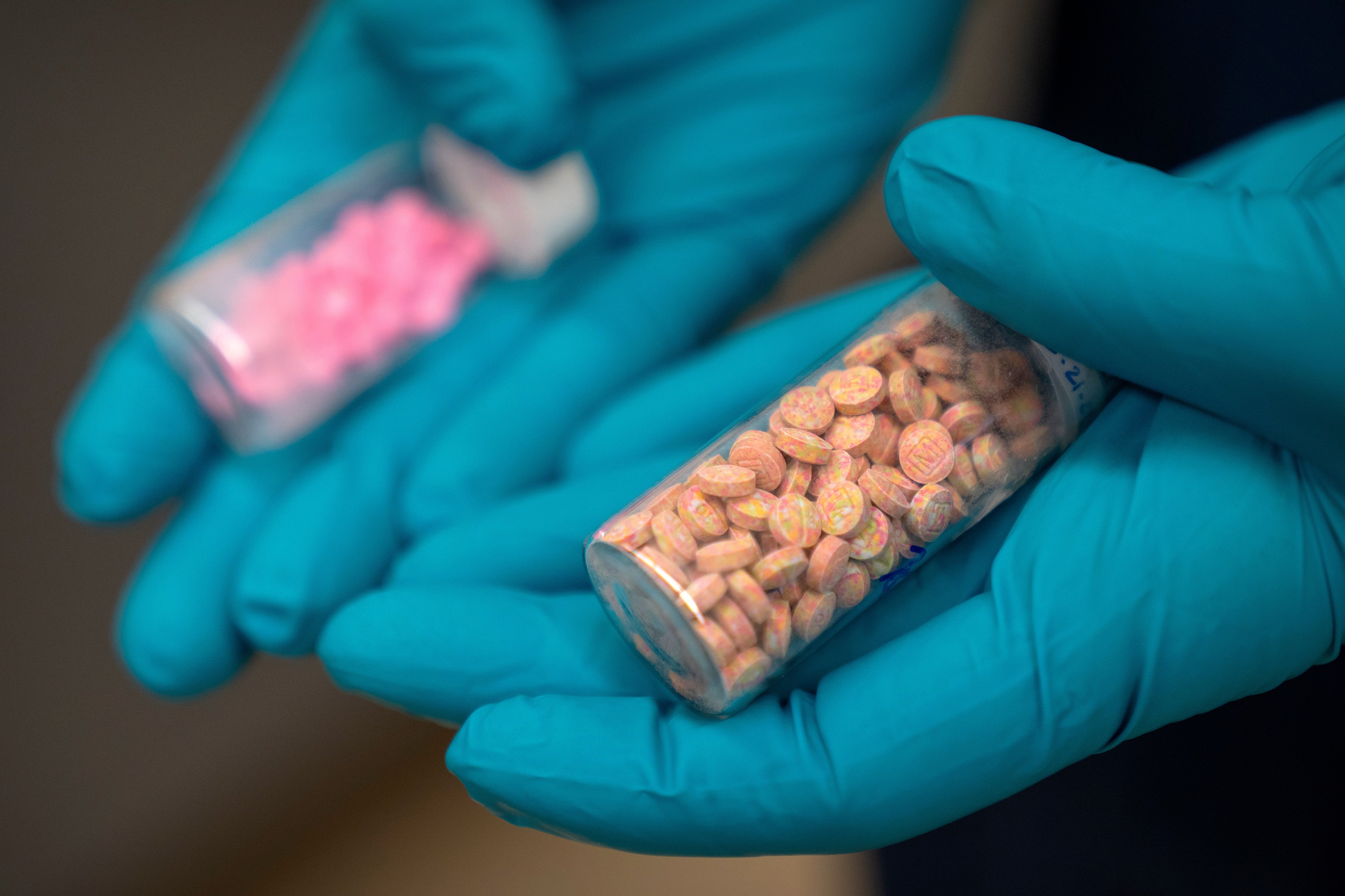 Jonathan Dumke, a senior forensic chemist with the Drug Enforcement Administration, holds vials of fentanyl pills at a DEA research laboratory