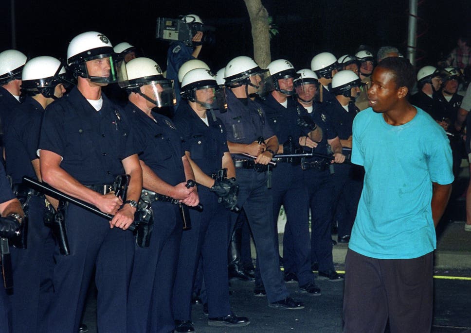 A man passes in front of a line of policemen in Los Angeles during the 1992 riots