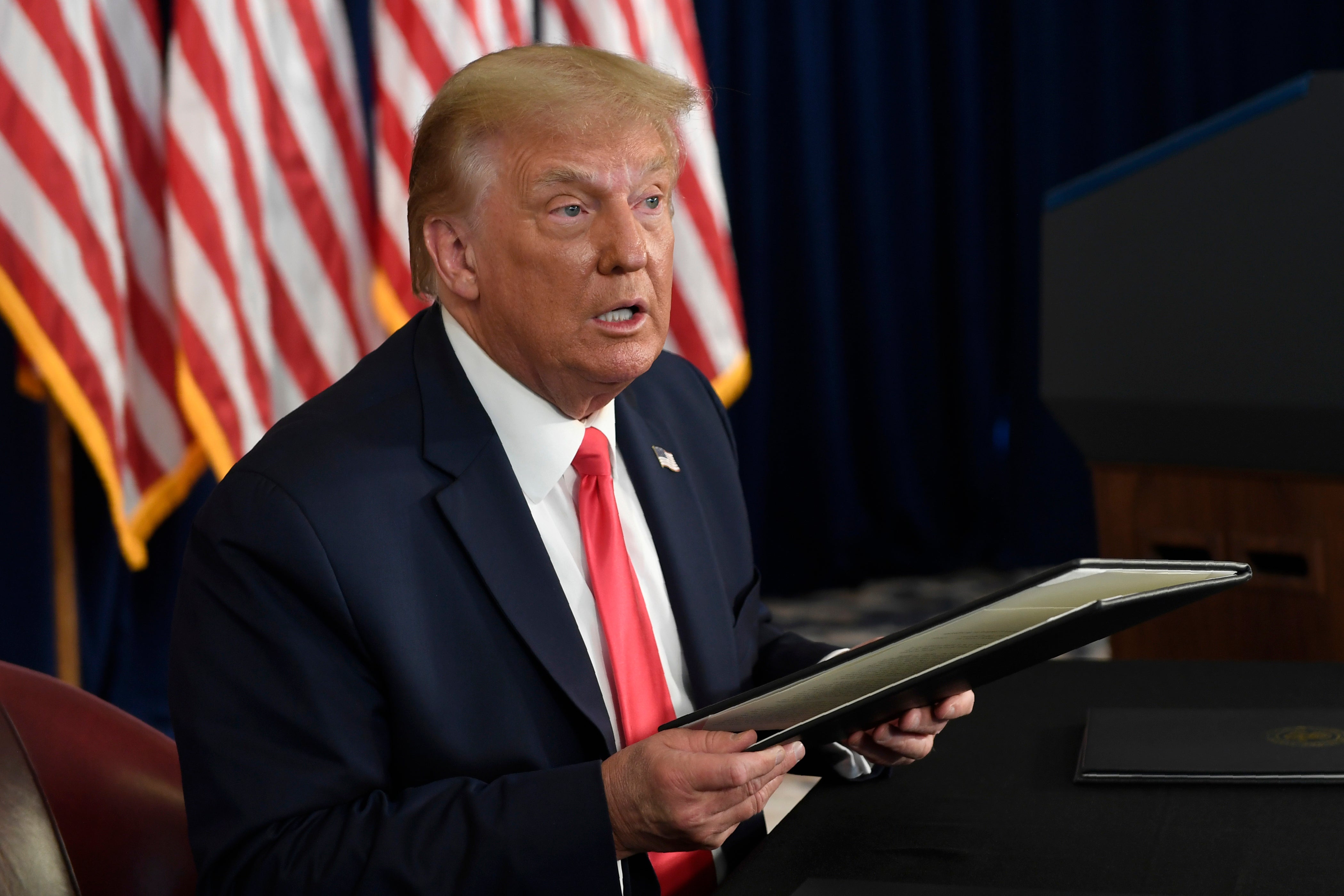 President Donald Trump prepares to sign four executive orders during a news conference at the Trump National Golf Club in Bedminster