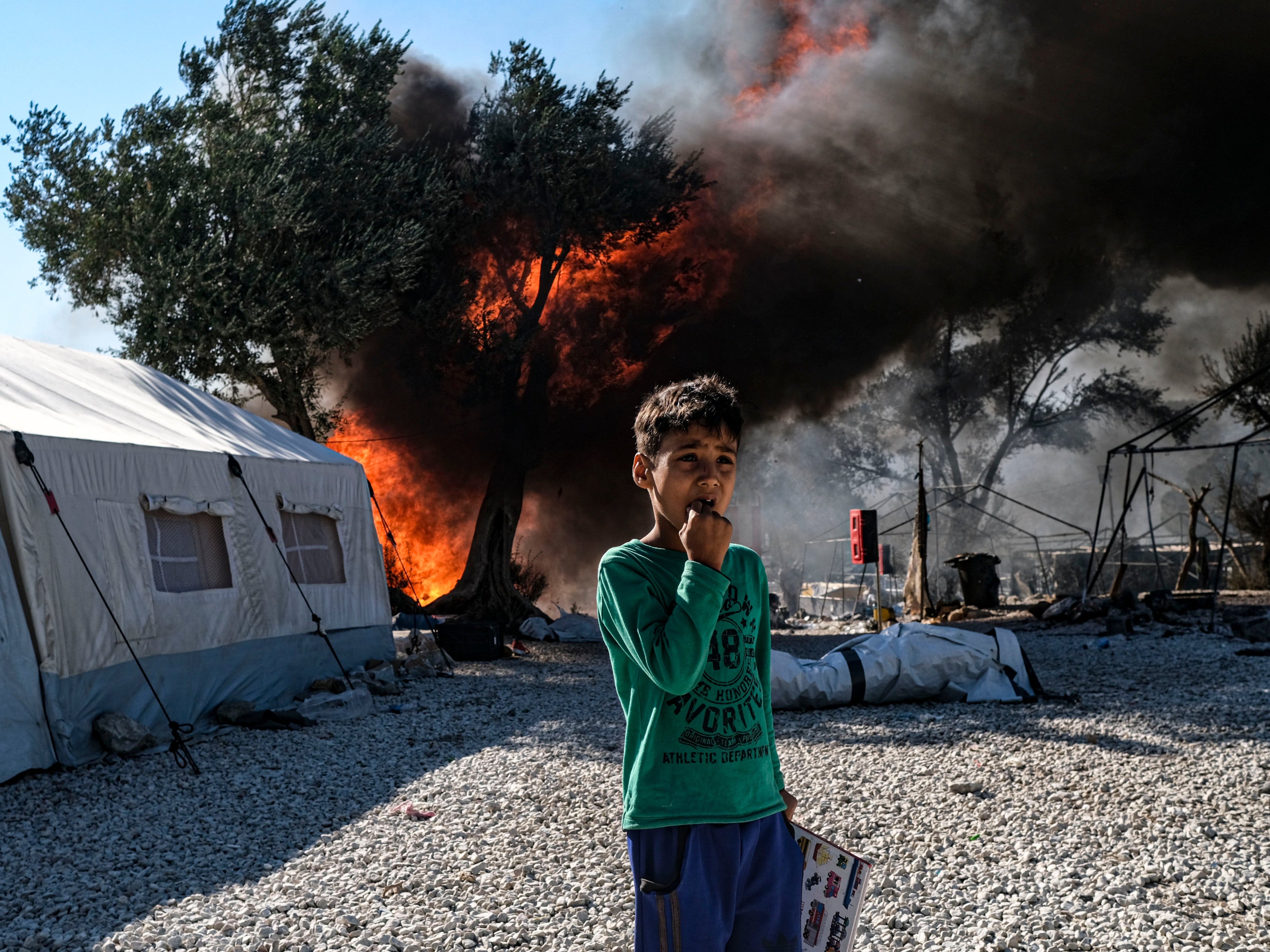 An Afghan asylum-seeking boy looks on as fires which started on Tuesday night continue to rage into Thursday morning inside of Moria camp