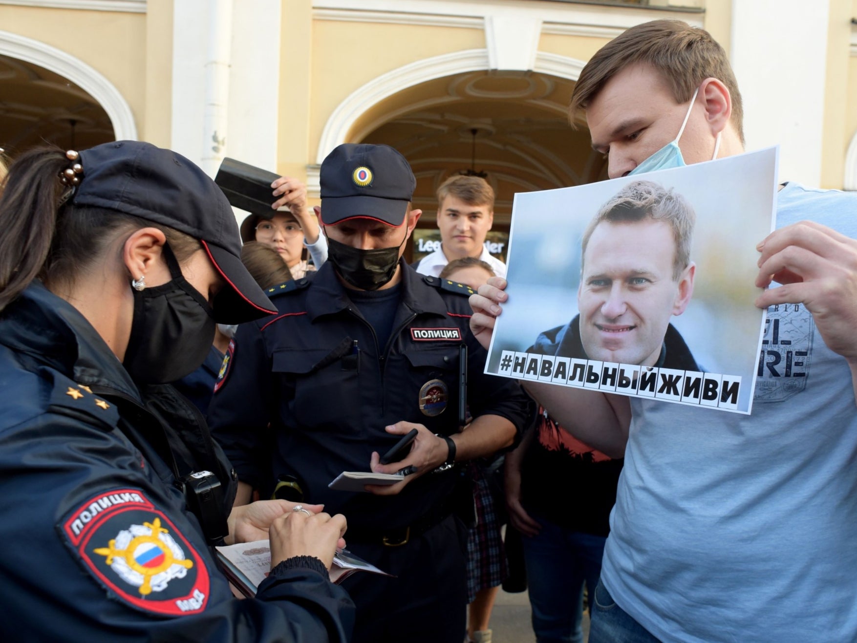 A supporter of Navalny has his documents checked by police in the wake of his hospitalisation