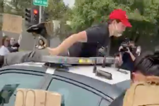 One injured at anti-Trump demonstration after police car speeds off with protester on roof