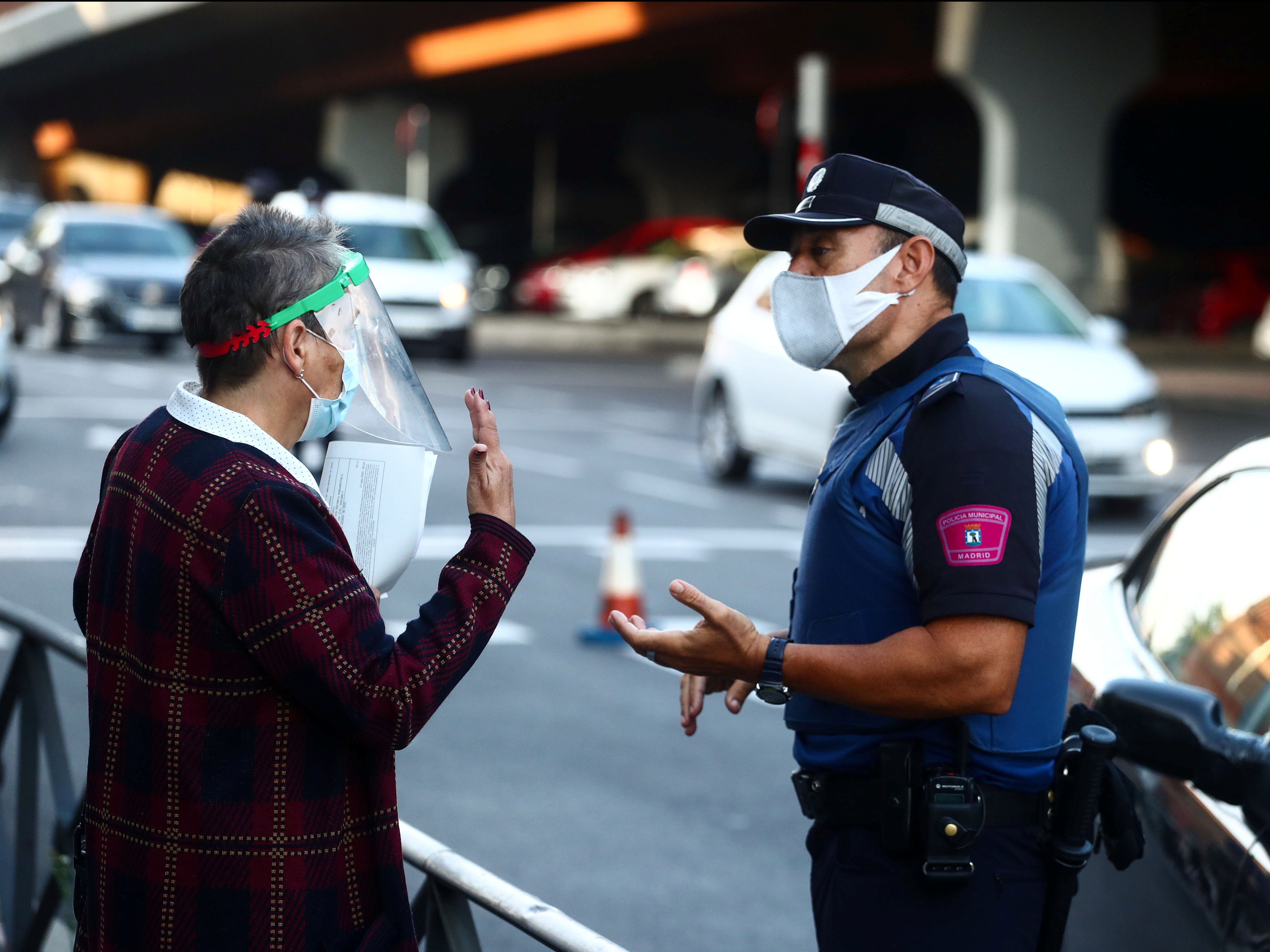 A local police officer speaks with a woman during the first day of partial lockdown in Madrid