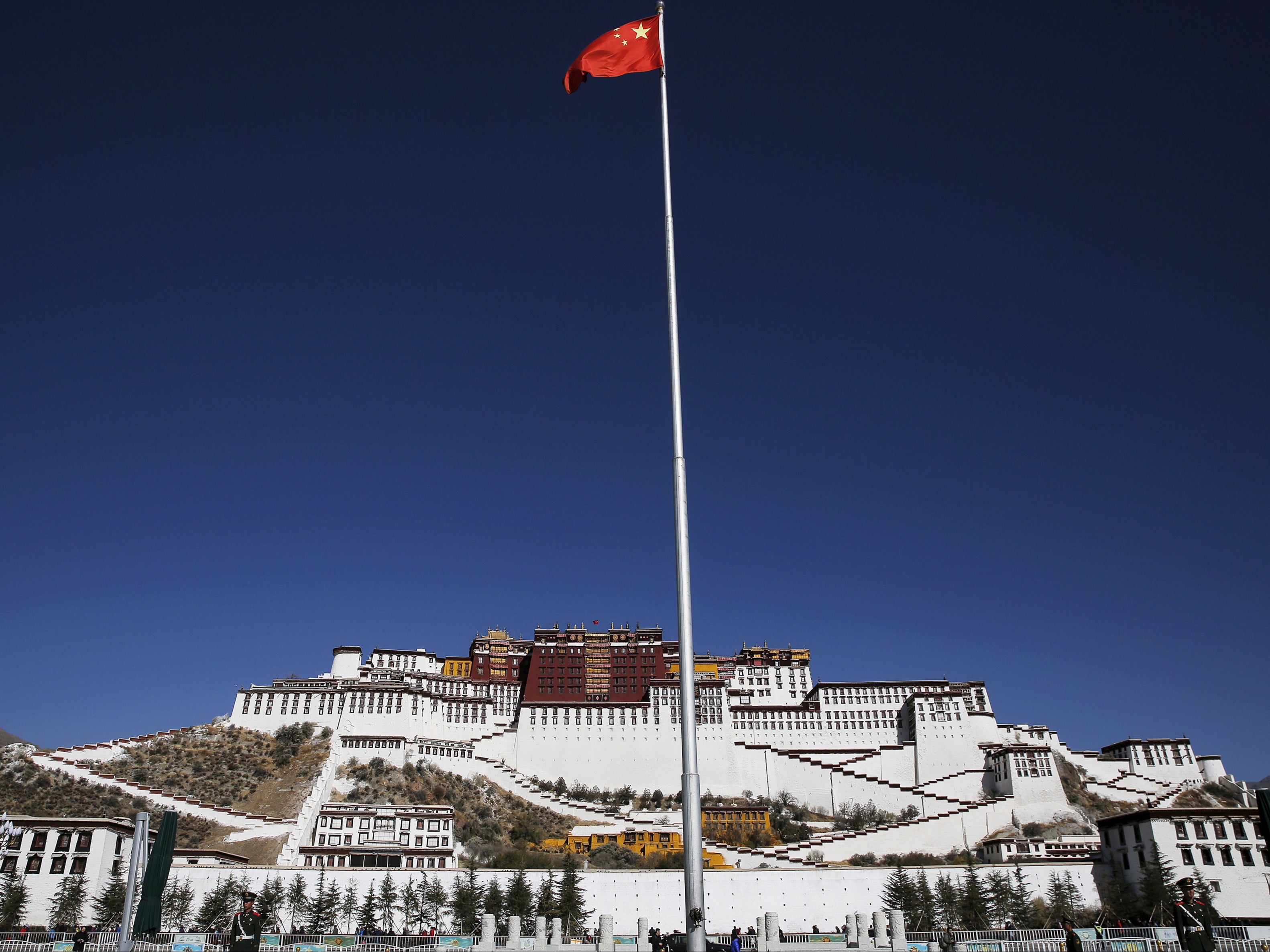 A Chinese flag flutters on a pole in front of the Potala Palace in Lhasa, Tibet Autonomous Region