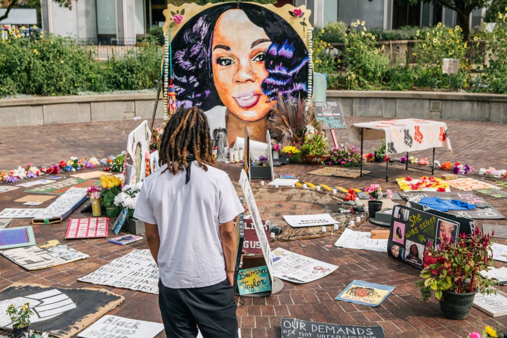 A man looks over a memorial dedicated to Breonna Taylor , who was killed during a police raid on her home