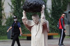 Sculpture of John Paul II with rock, red water makes waves