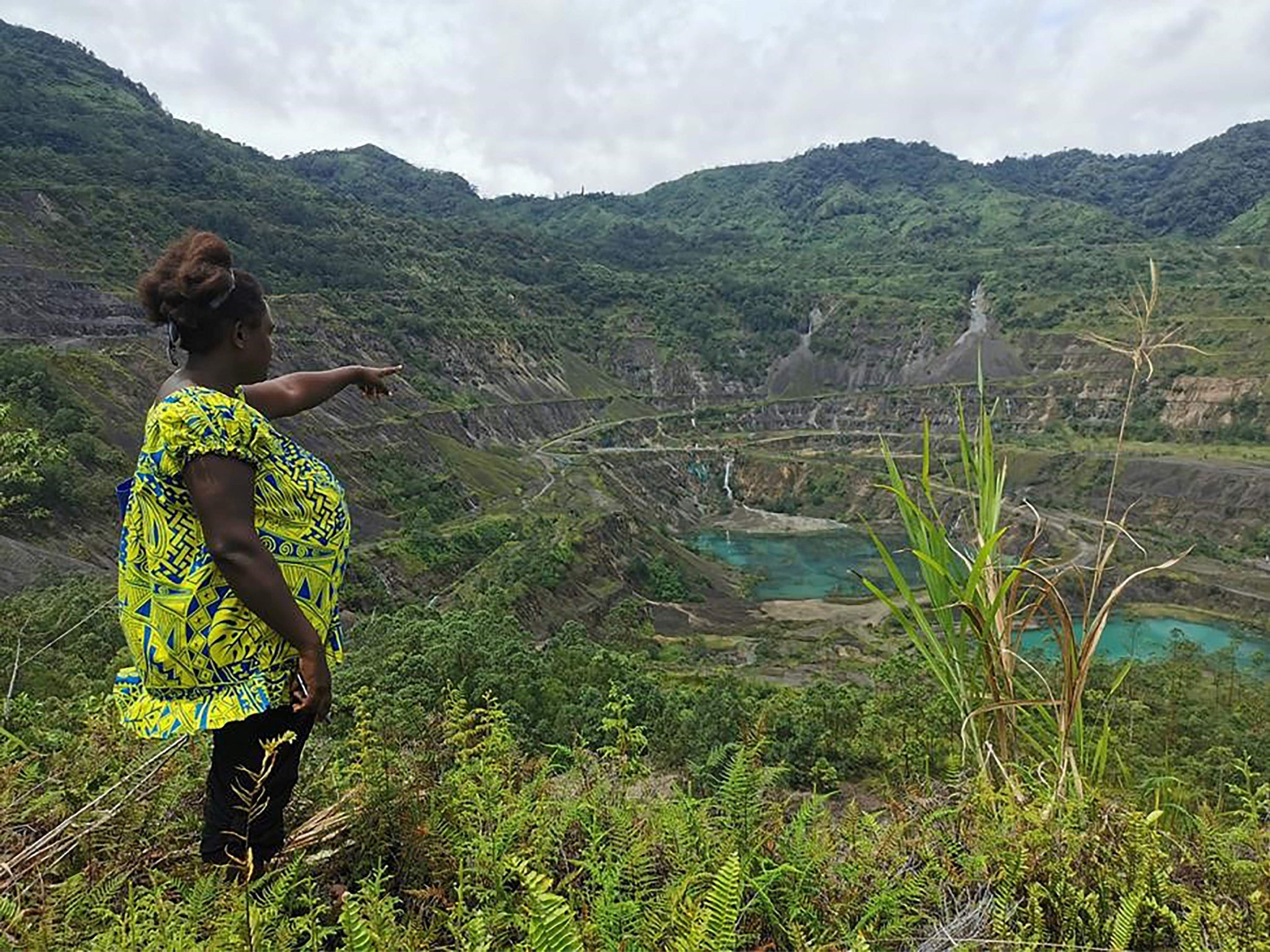 Local resident and advocacy group member Theonila Roka Matbob standing in front of the abandoned Panguna mine pit in Bougainville