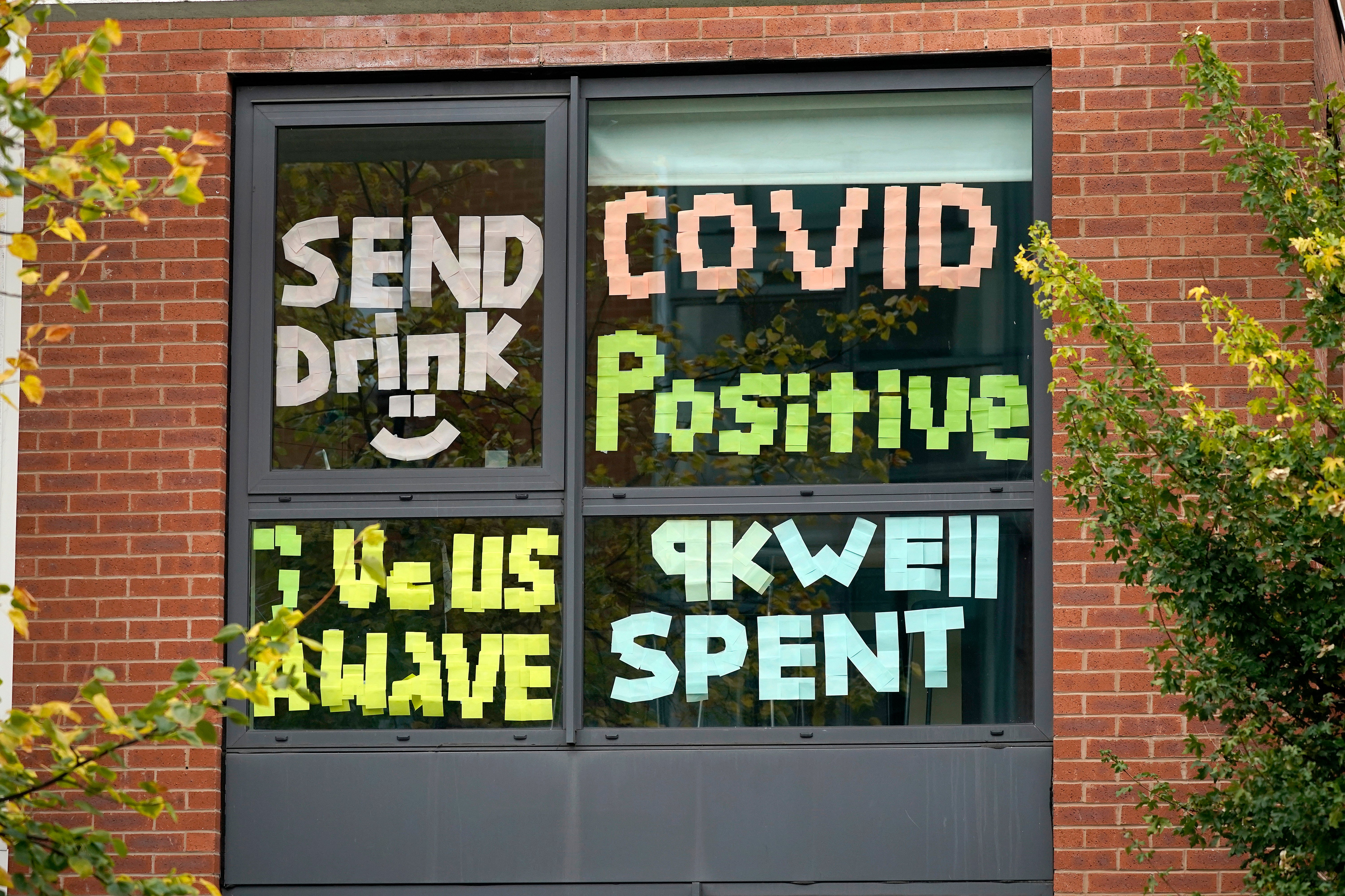 Signs made by students are displayed in a window of their locked down accommodation building in Manchester