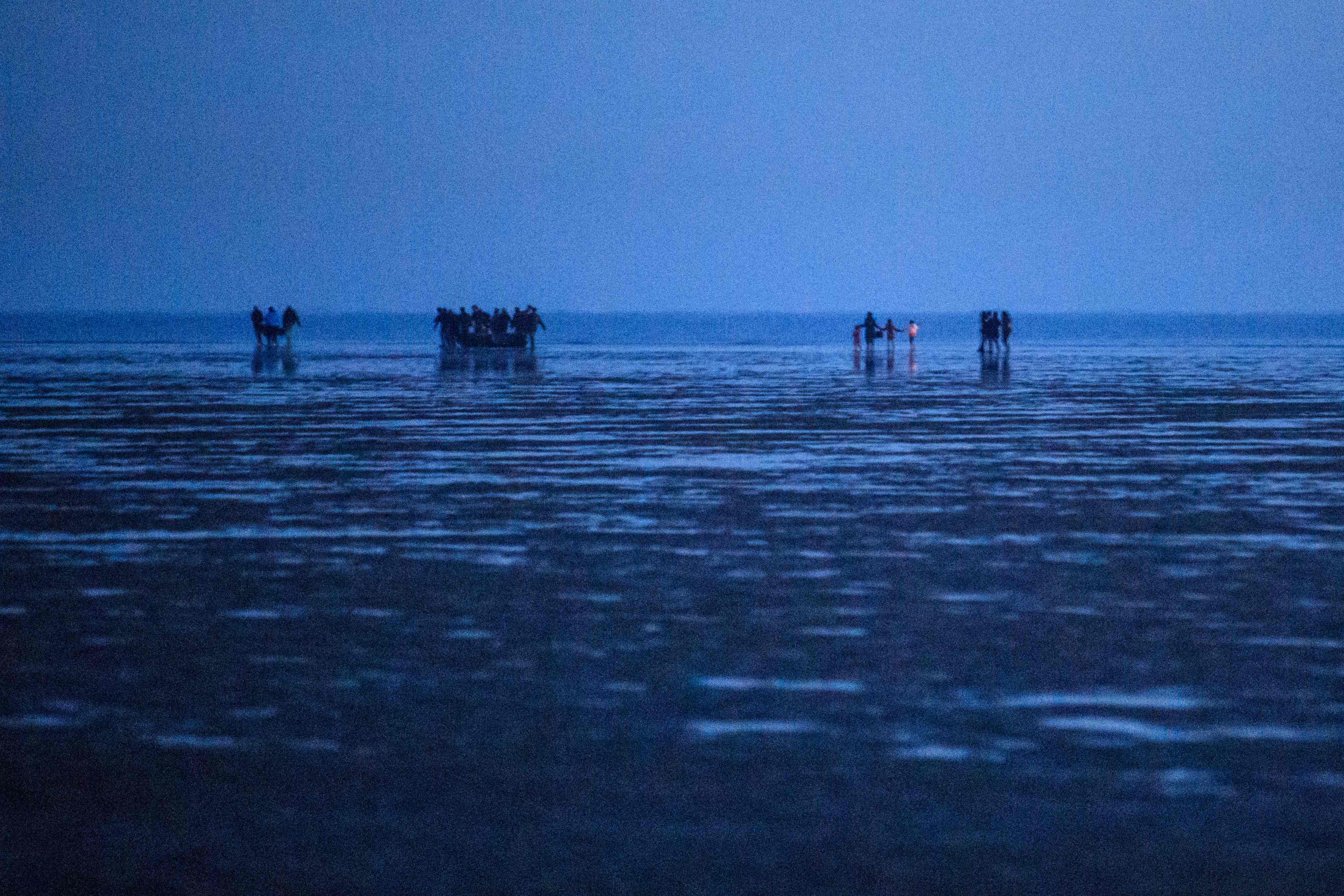 Migrants carry a boat and engine to sea in Dunkirk, northern France