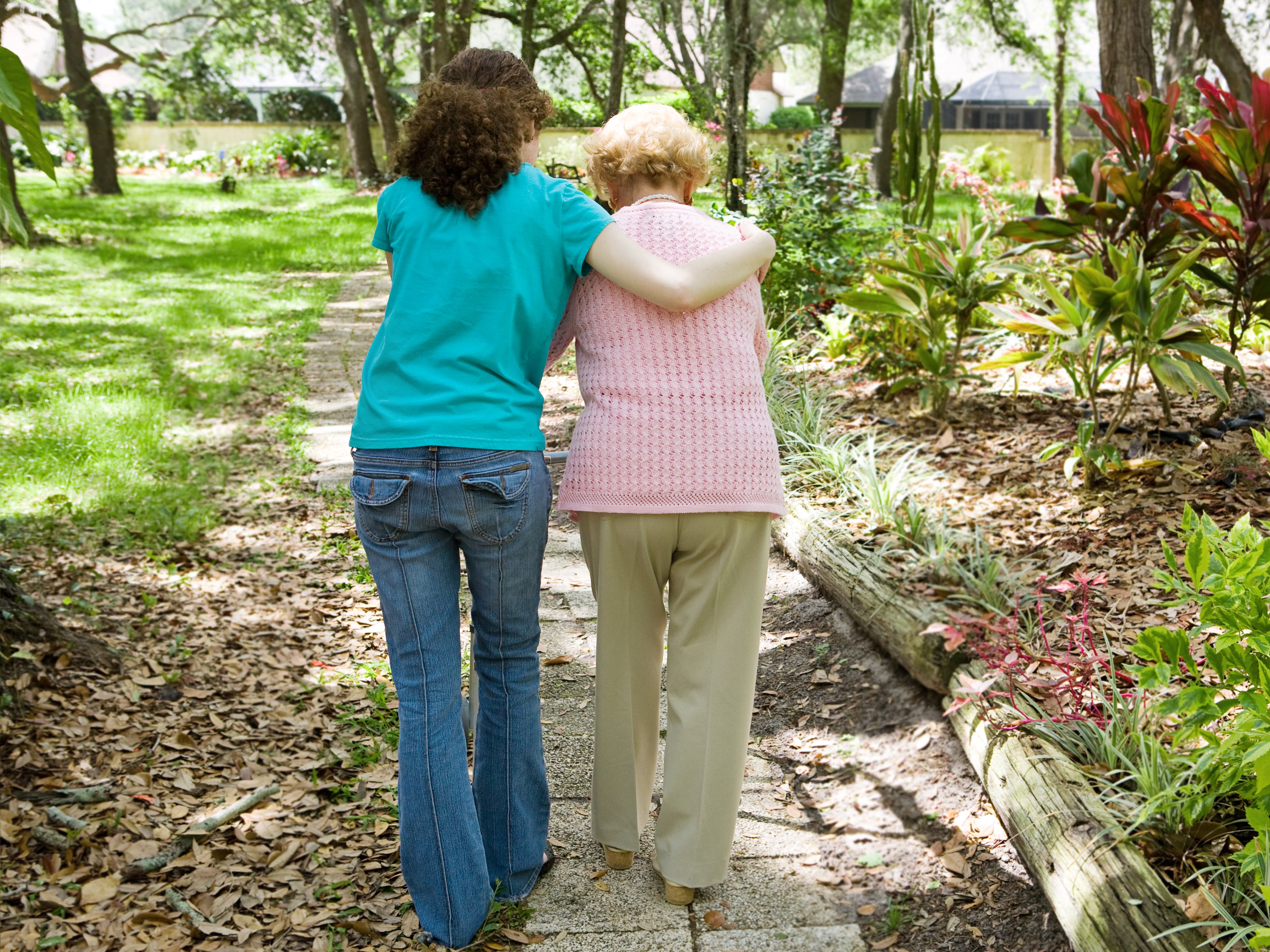 Granddaughter helps her grandmother, who has dementia, to walk with the aid of a walker