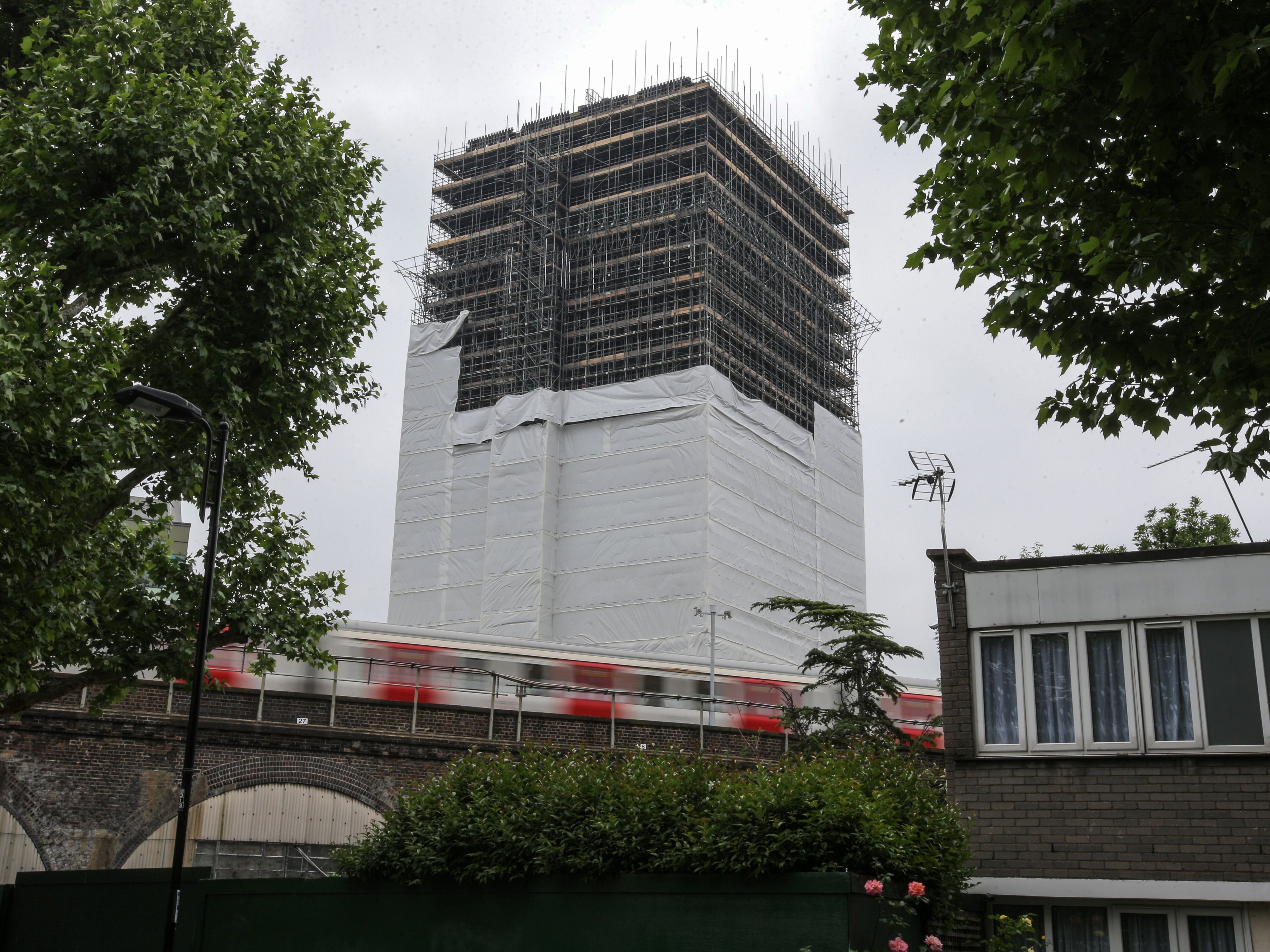 A tube train passes the burned-out shell of Grenfell Tower block in west London