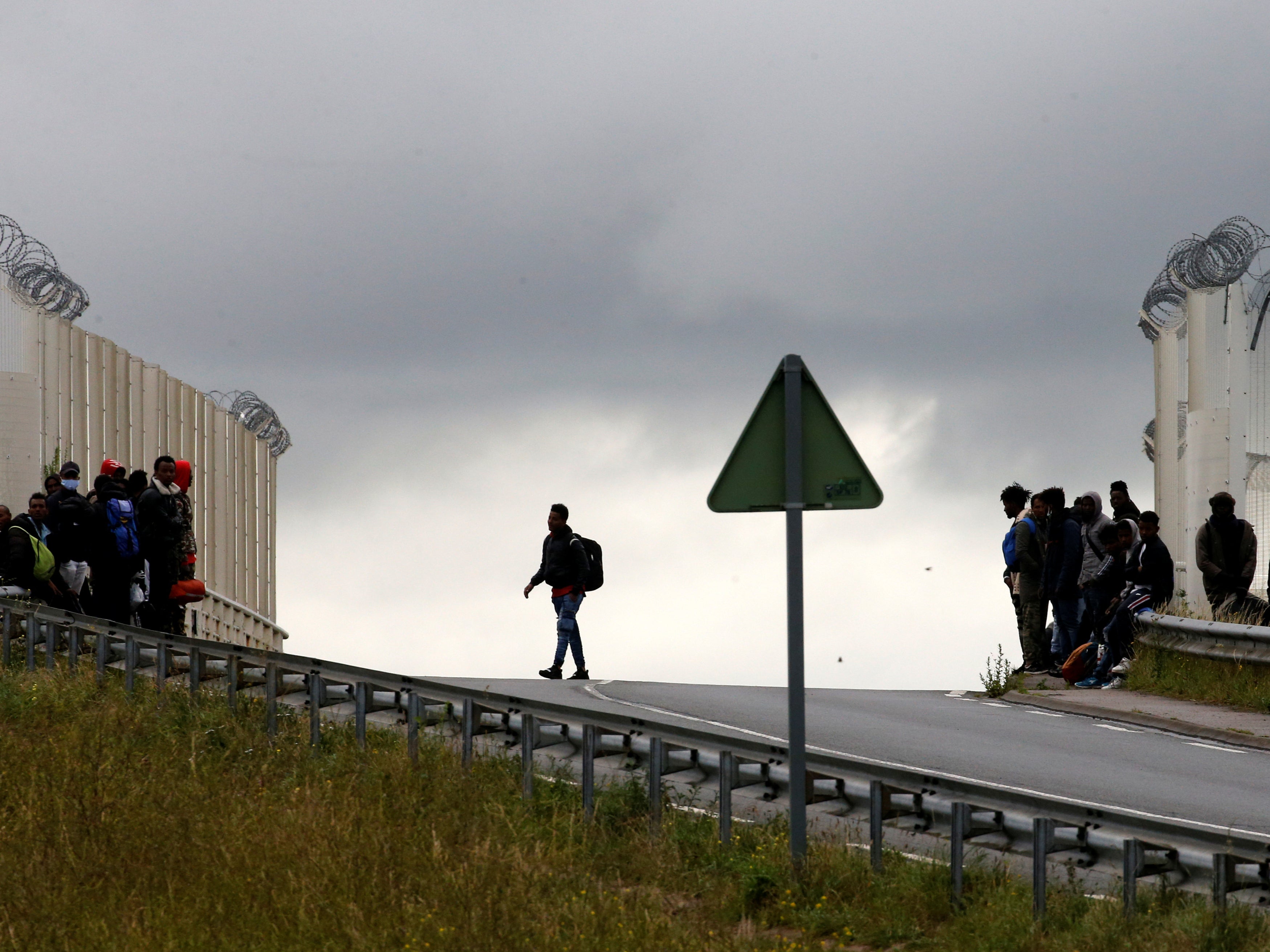 Migrants leave as French police officers dismantle a makeshift shelter camp in Calais