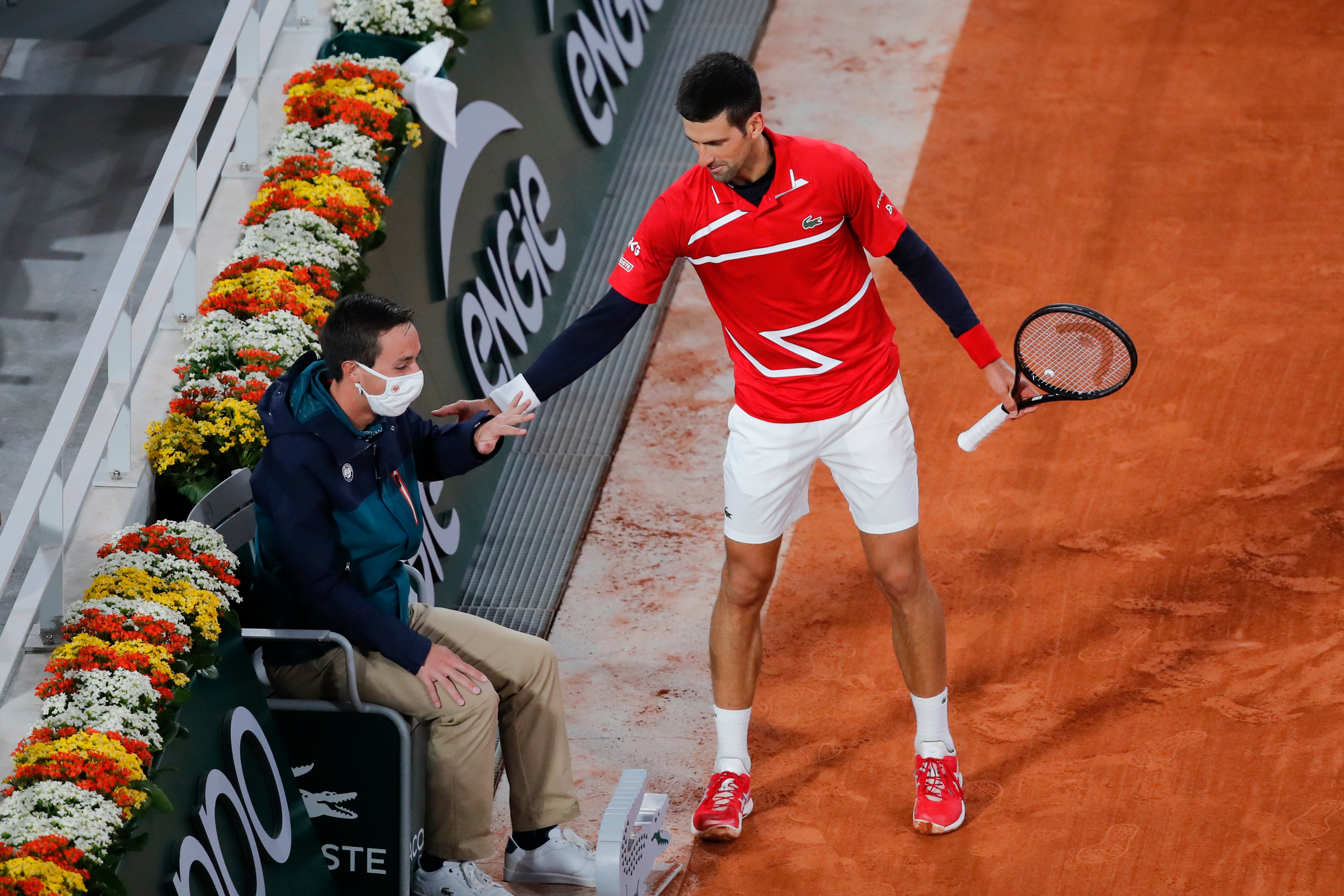 Novak Djokovic apologises to a line judge after striking him with the ball during a point at the French Open