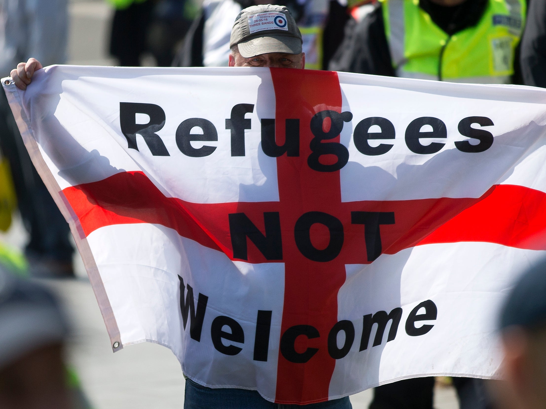 A protestor holds up a flag that reads "Refugees Not Welcome" during a demonstration in Dover