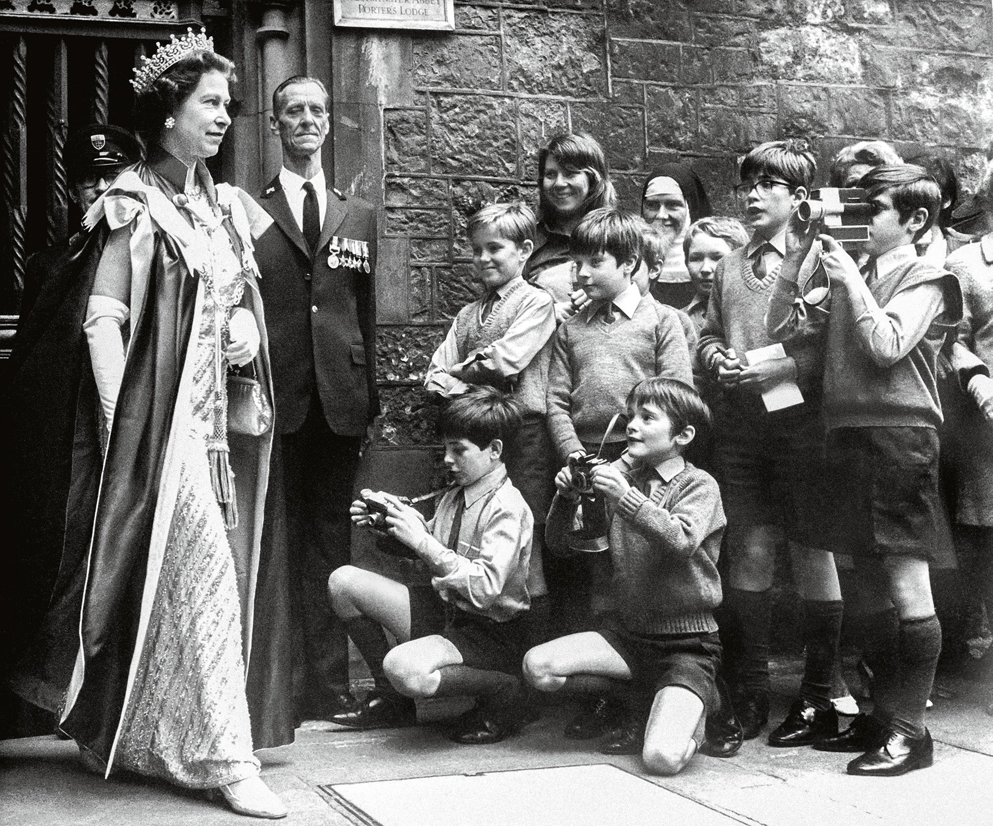 The Queen is photographed by boys of the Westminster Abbey choir school as she leaves the Abbey after a service for the Order. 1972.
