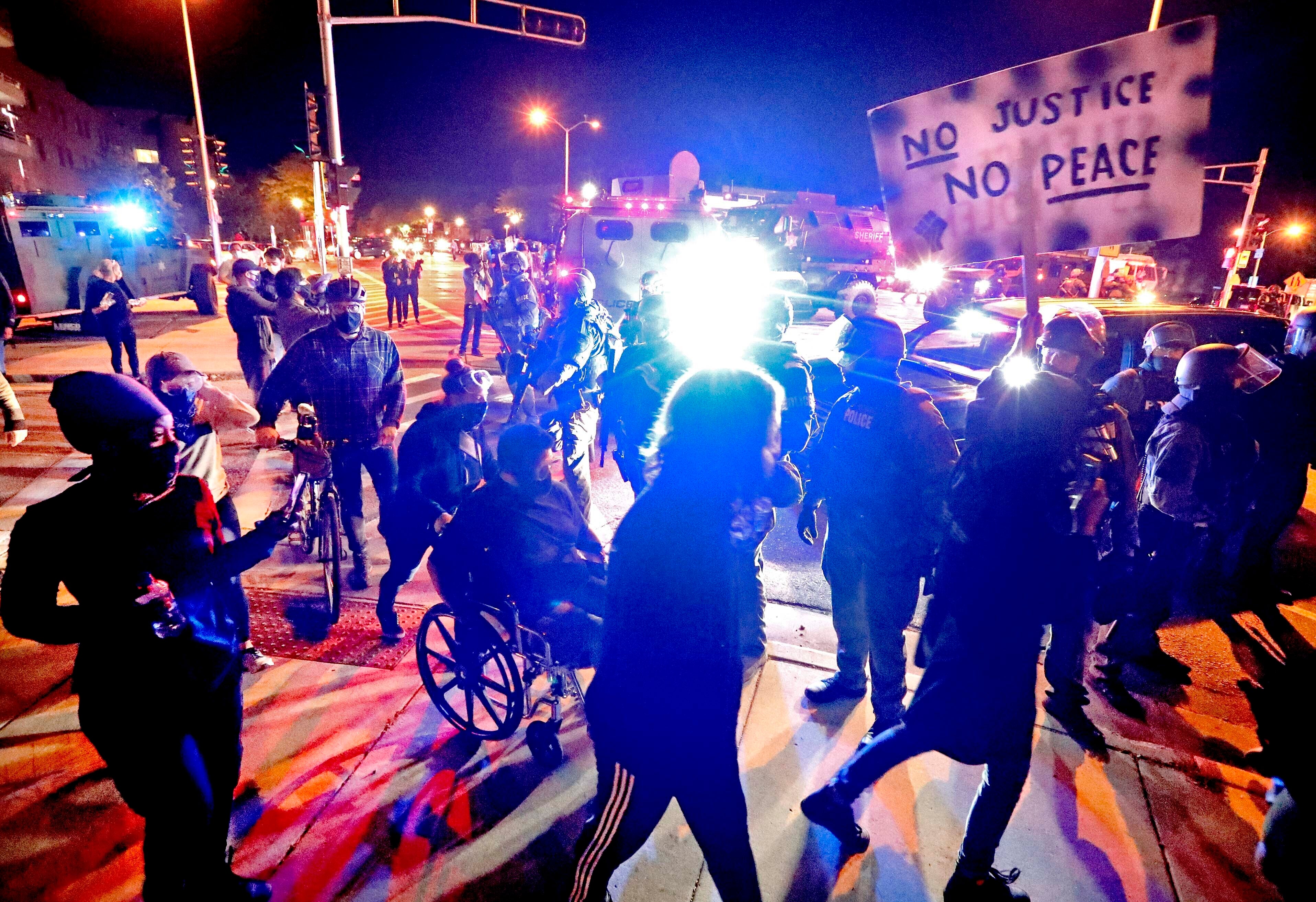 Protesters march in Wauwatosa, Wis., around a line of National Guardsmen protecting the Wauwautosa City Hall on Wednesday night.