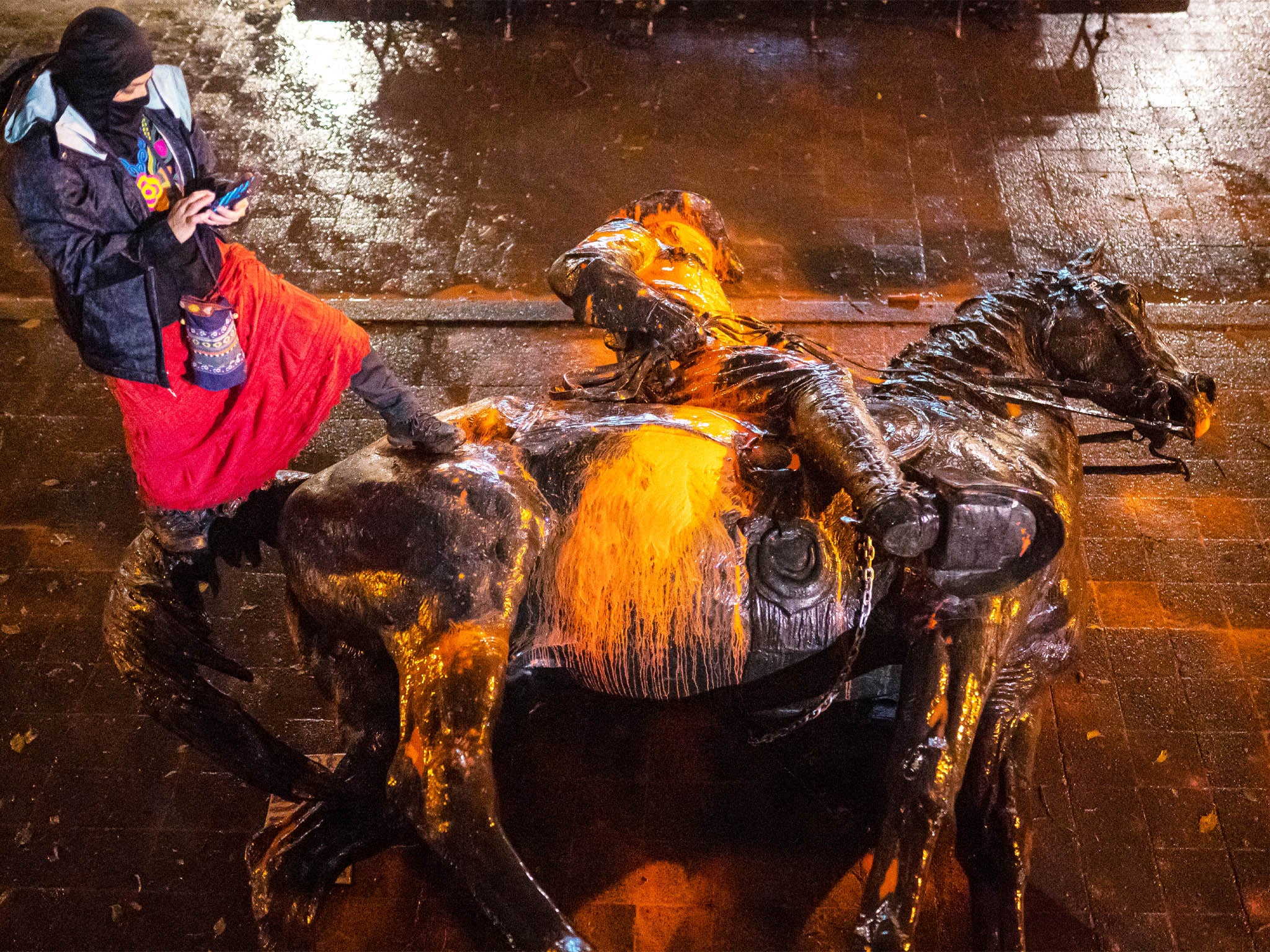 Protester stands over a toppled statue of President Theadore Rosevelt on 11 October