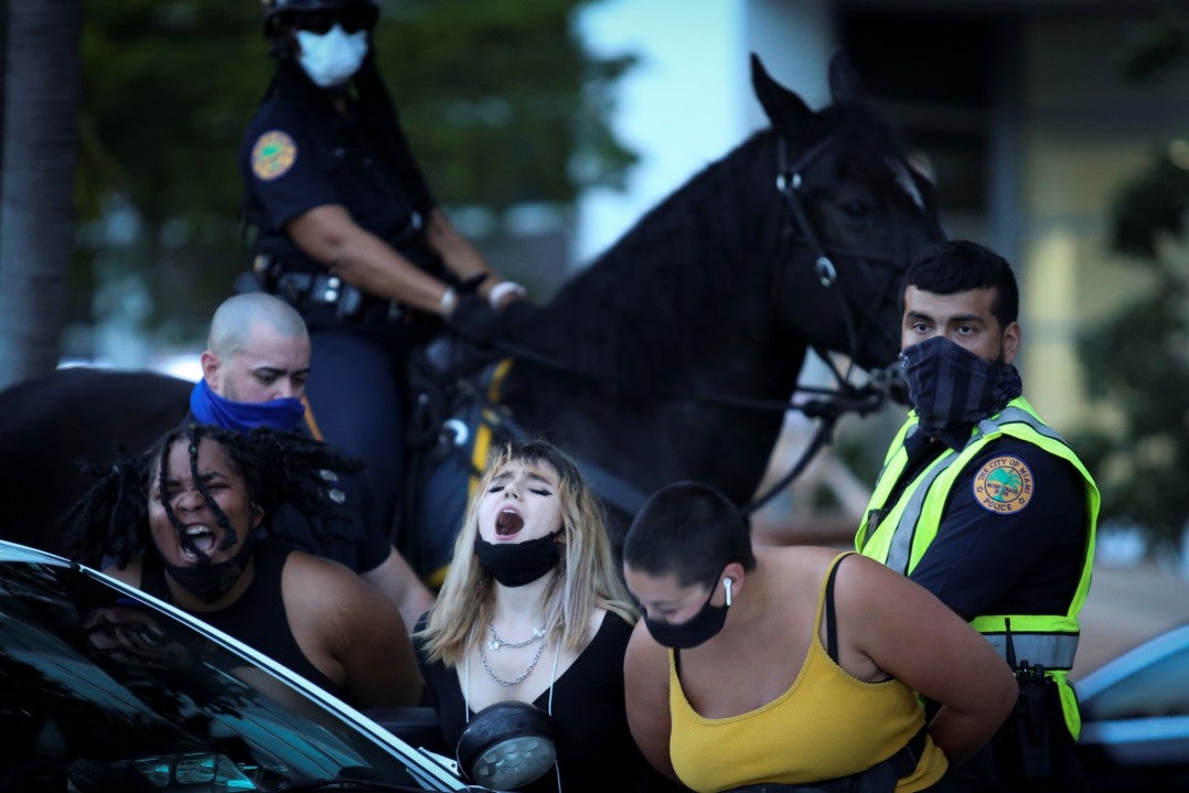 Miami Police officers detain demonstrators protesting against president Donald Trump