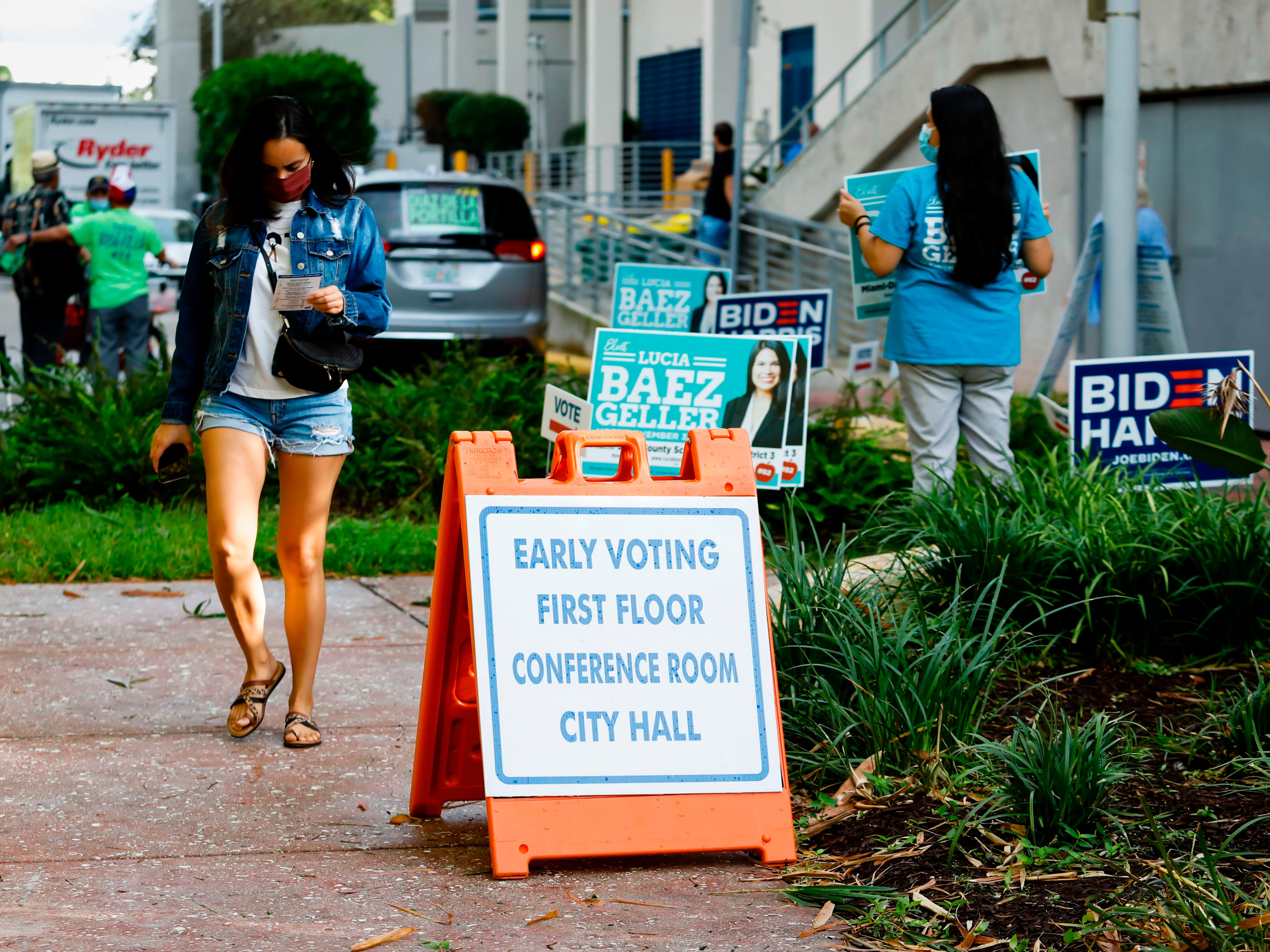 A woman walks past an Early Voting sign at Miami Beach City Hall in Miami Beach, Florida, where voting records have just been broken