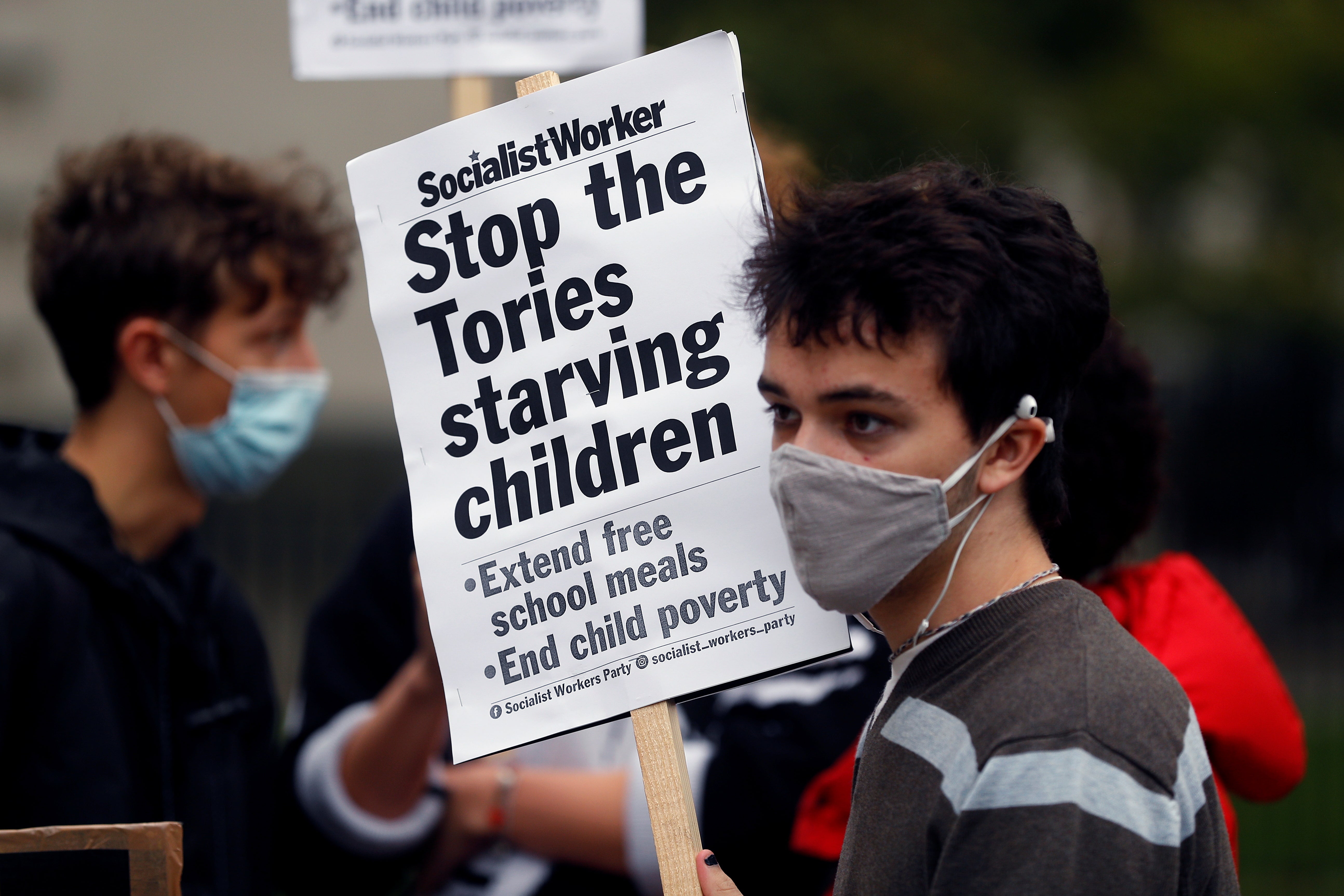 A boy holds a banner during a protest demanding free school meals for children in England