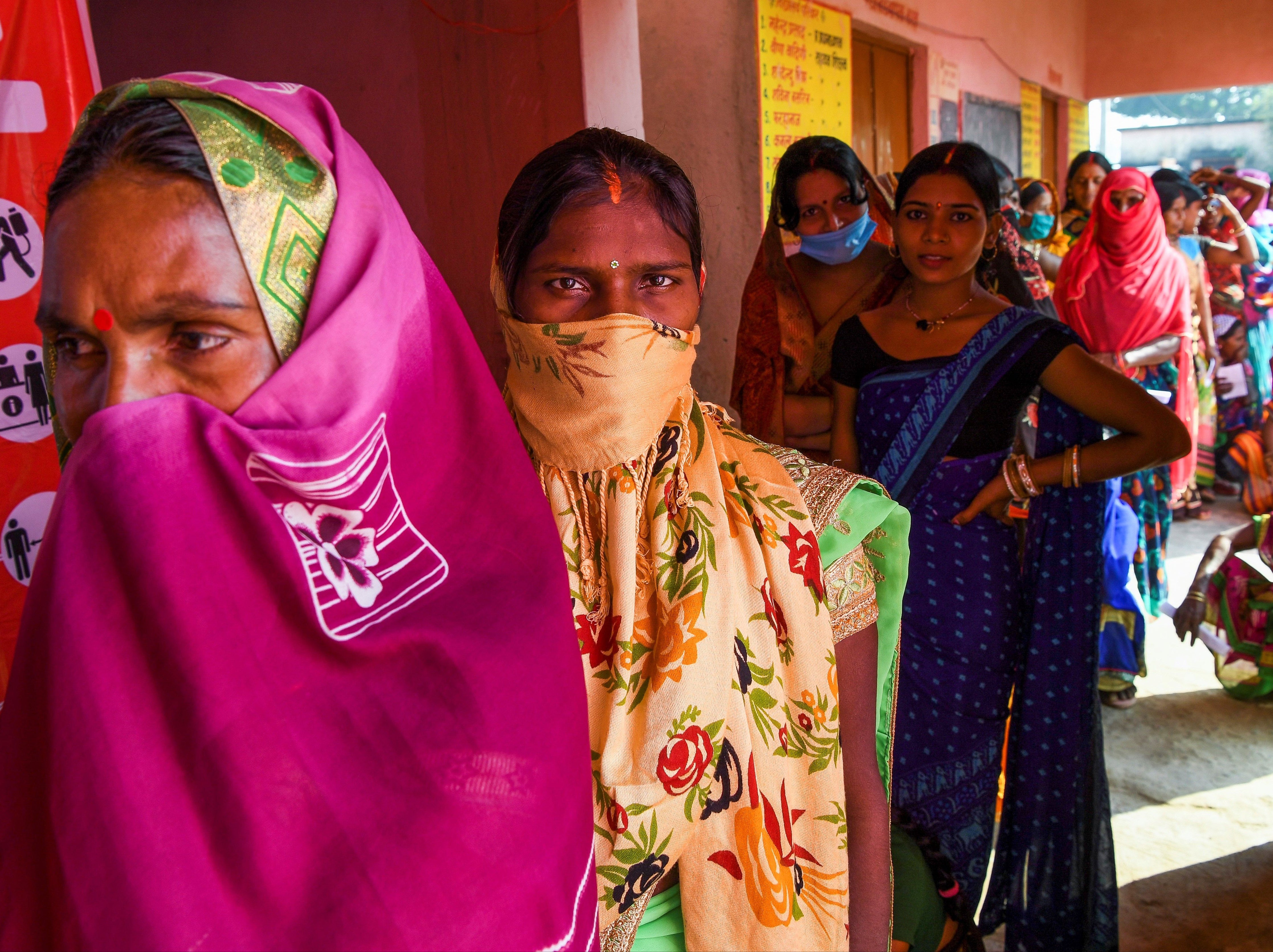 Voters queue up to cast their ballots for Bihar state assembly elections at a polling station