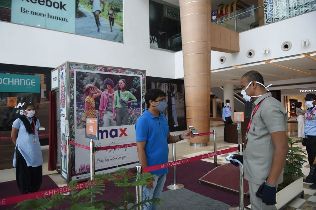 A member of the internal medical team checks the Aarogya Setu app on the mobile phone of a staff at the entrance of the Ahmedabad One Mall