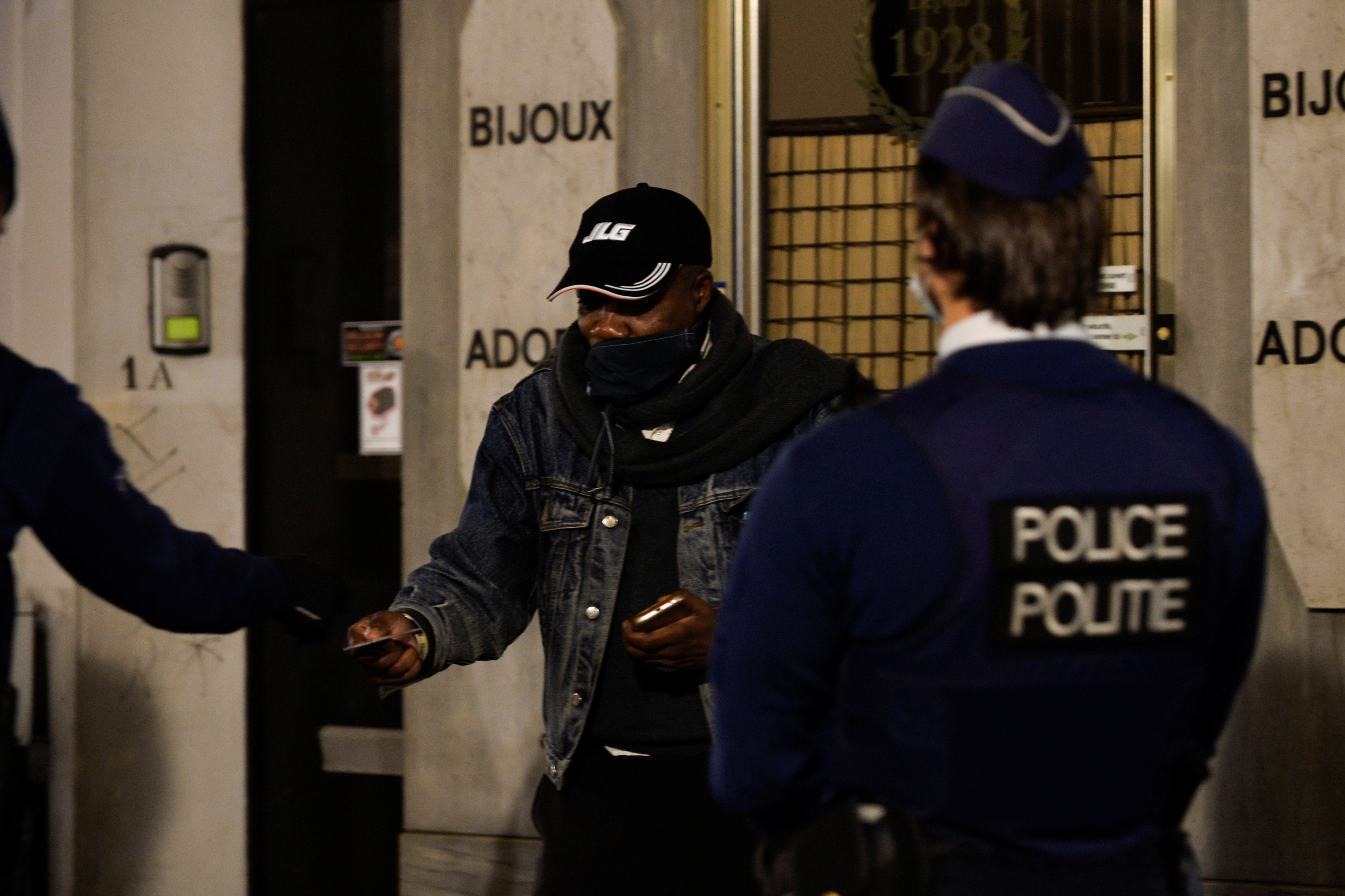 Police officers check the documents of a man while patrolling in central Brussels during a curfew imposed by the Belgian government