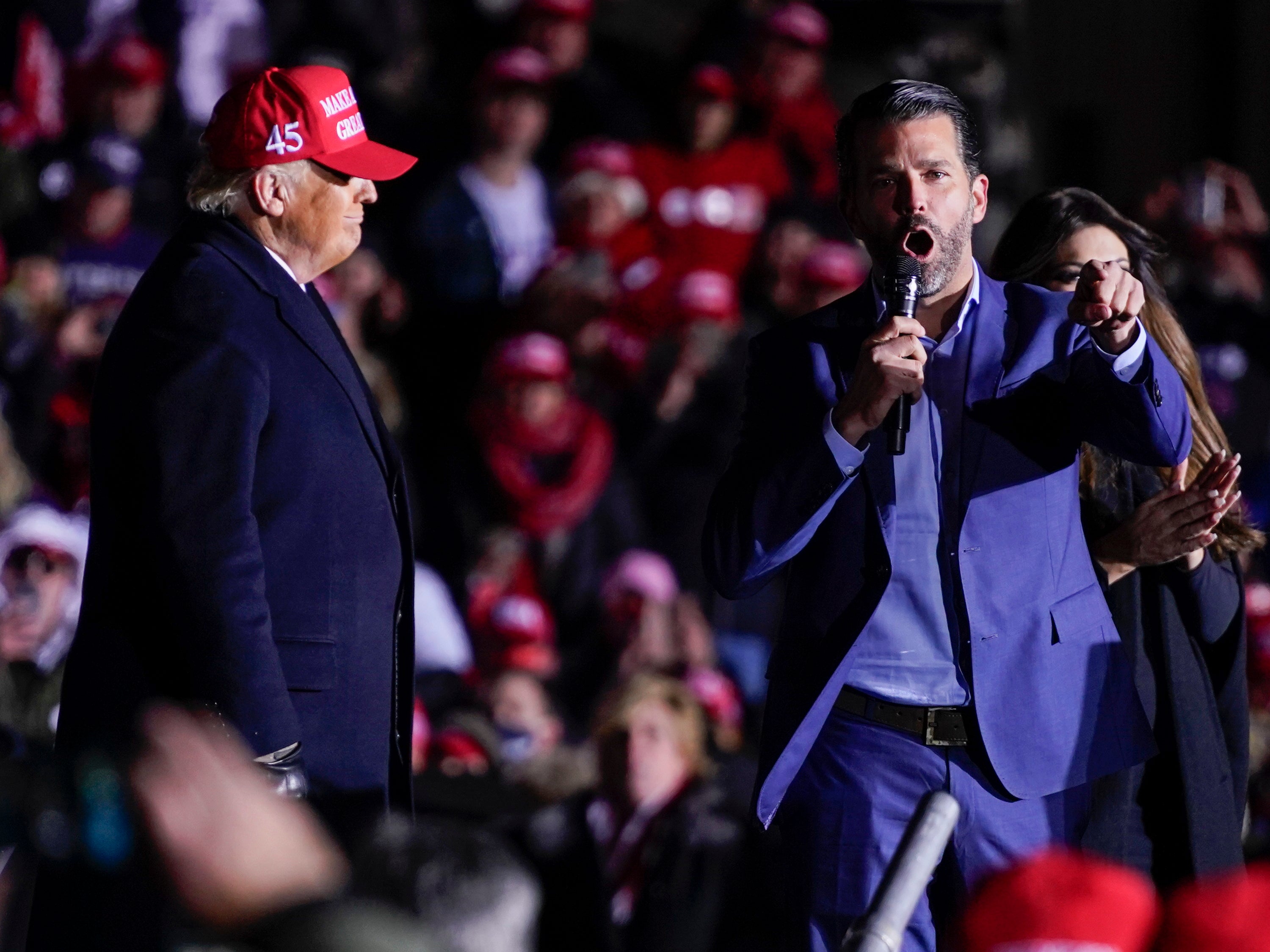 The US president listens as Donald Trump Jr speaks during a campaign rally at Kenosha regional airport