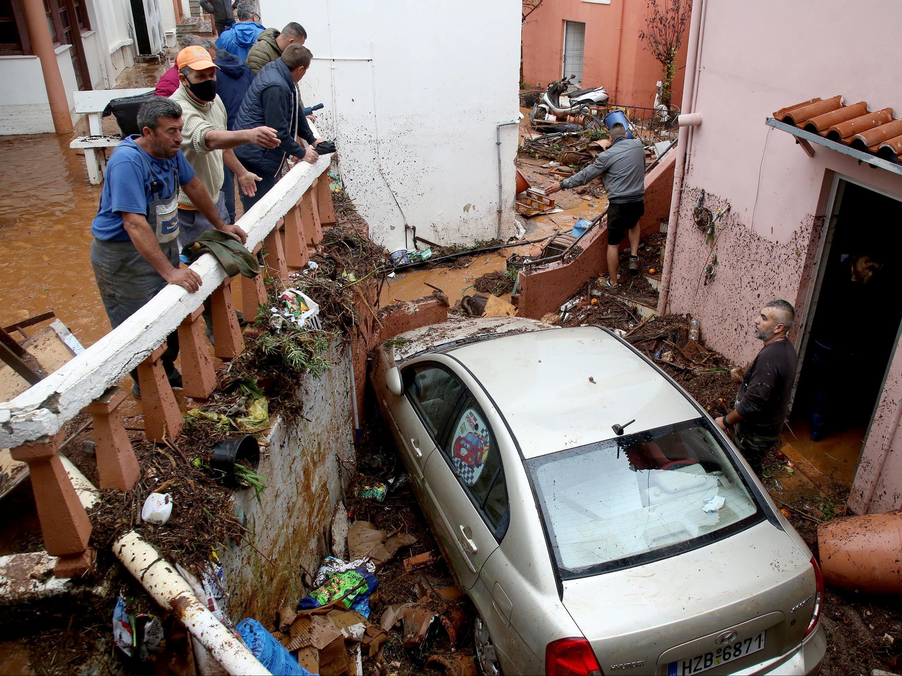 Locals in the village of Gournes stand in a yard full of debris following heavy rainfall on the island of Crete