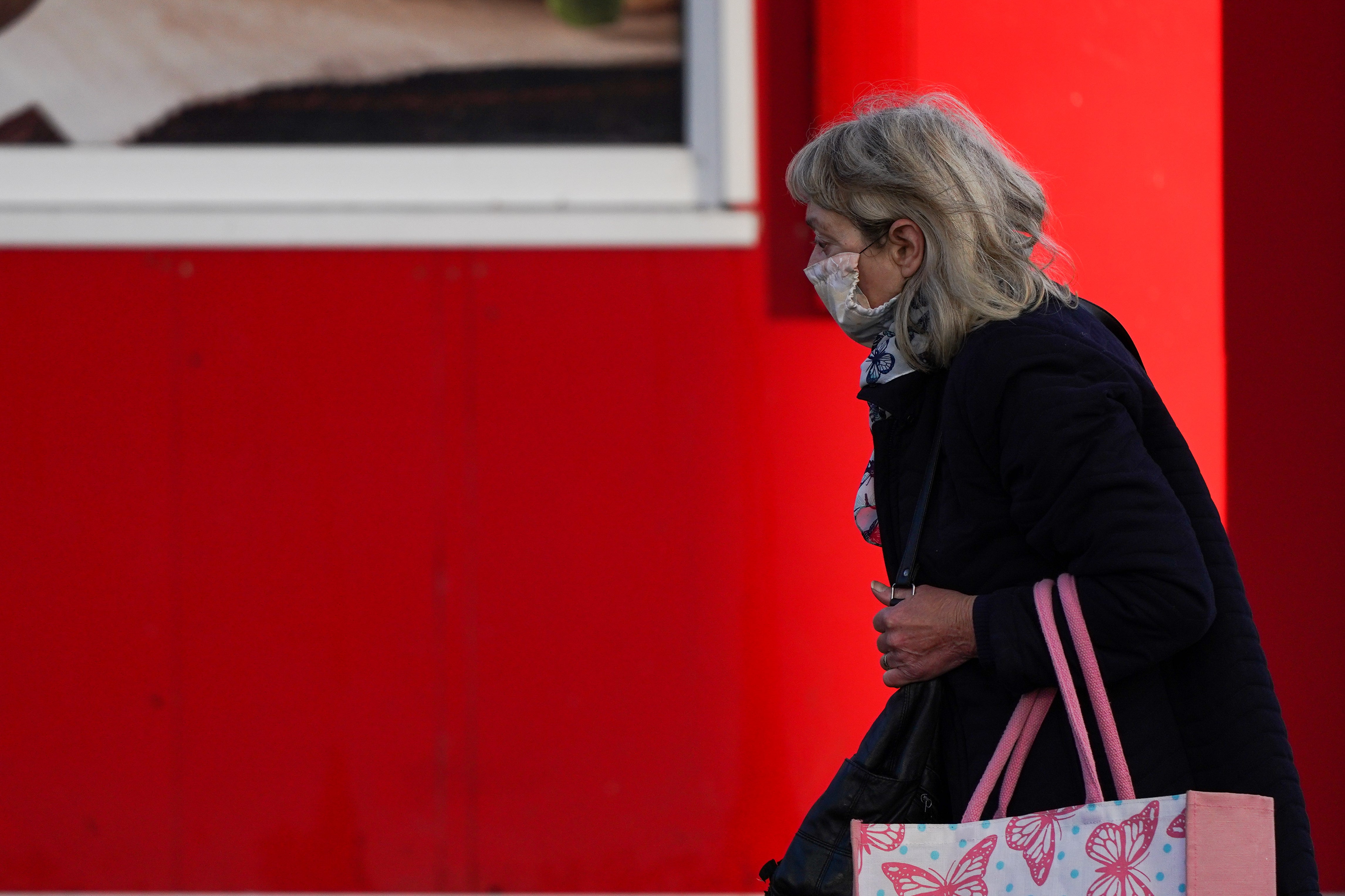 A woman wearing a face mask walks past shops in Hull on November 13, 2020 in Hull, England.