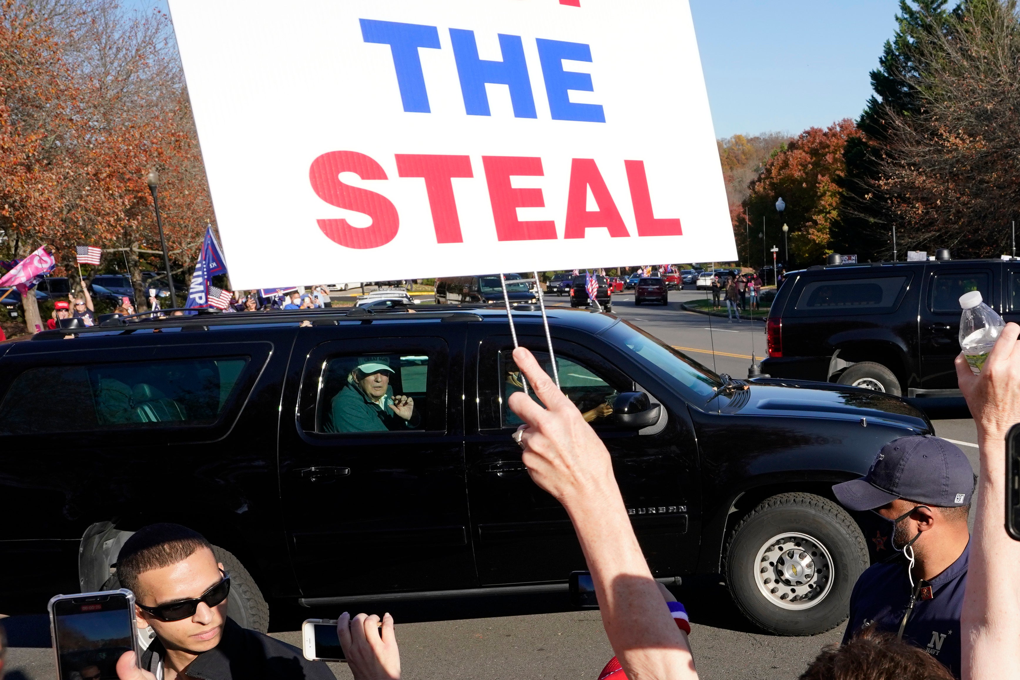 Leaving, but not quietly. President Donald Trump looks on to supporters after leaving the Trump National golf club in Sterling, Va