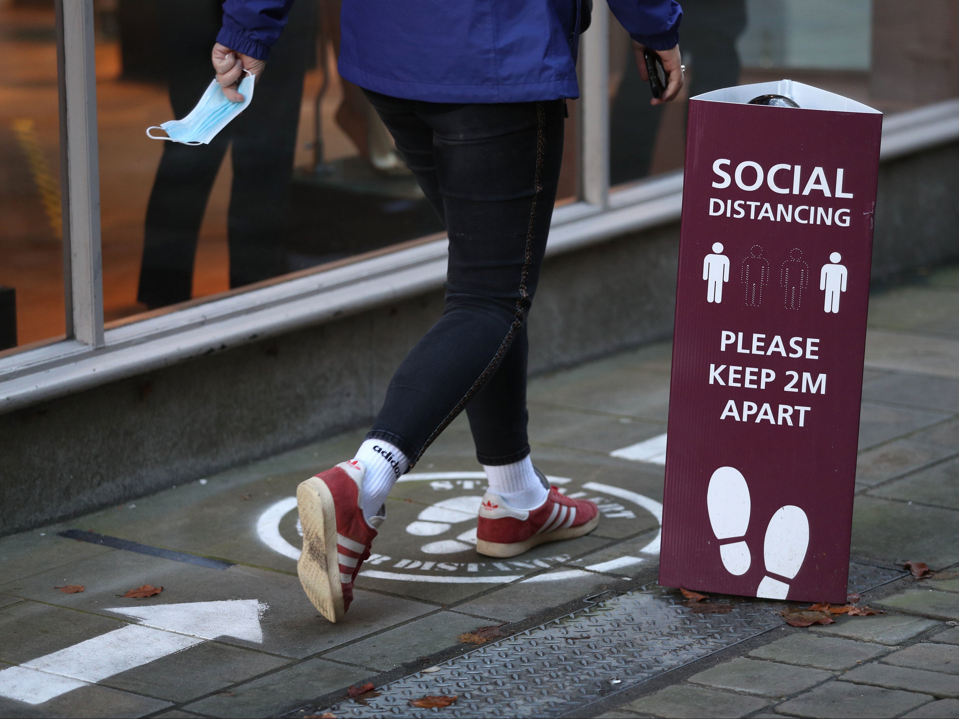 A person walks past a social distancing sign near the High Street in Winchester, Hampshire