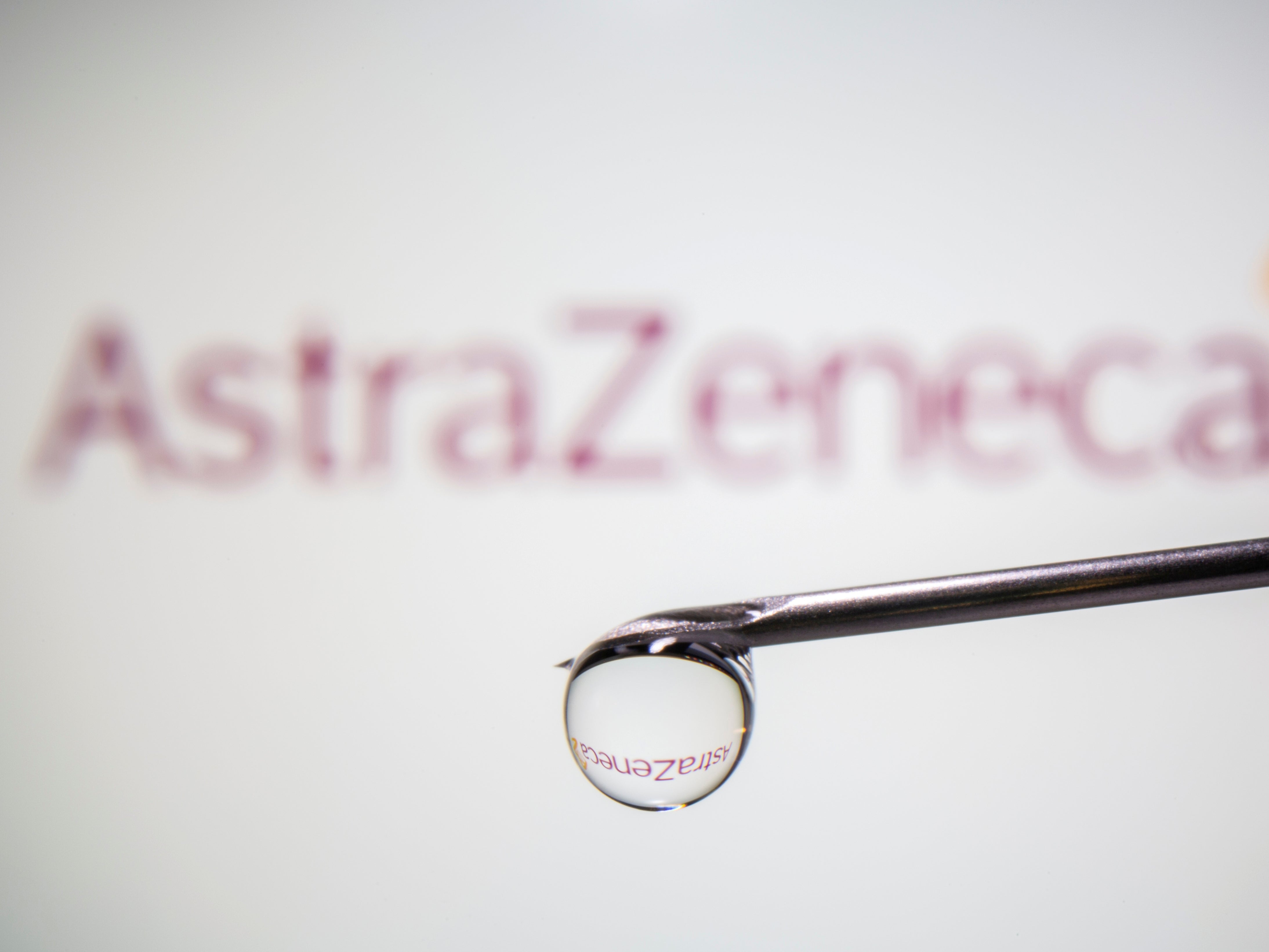 AstraZeneca's logo is reflected in a drop on a syringe needle in this illustration