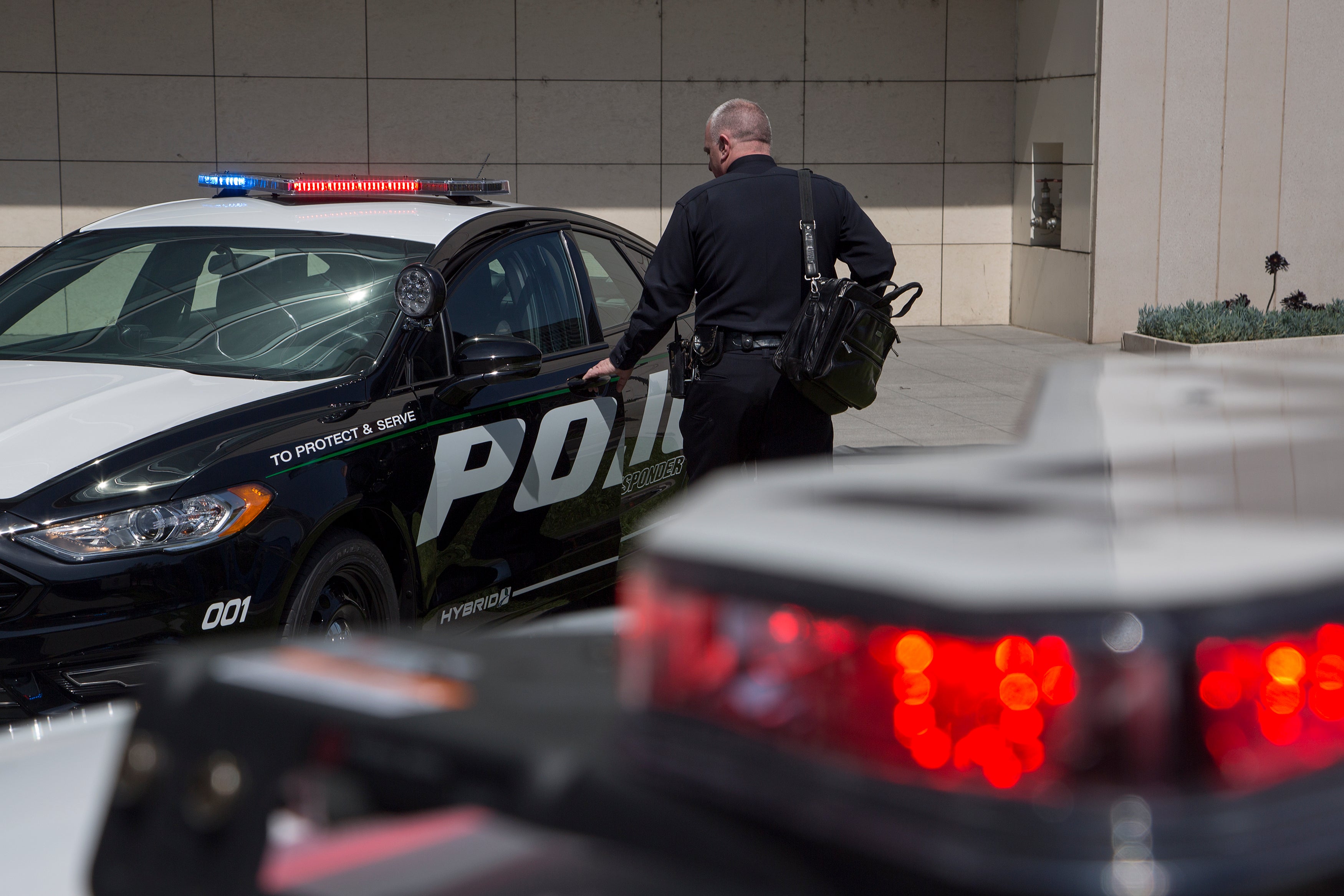 An LAPD officer looks at a car at the unveiling of two new Ford Fusion hybrid pursuit-rated Police Responder cars at Los Angeles Police Department headquarters on 10 April 2017 in Los Angeles, California