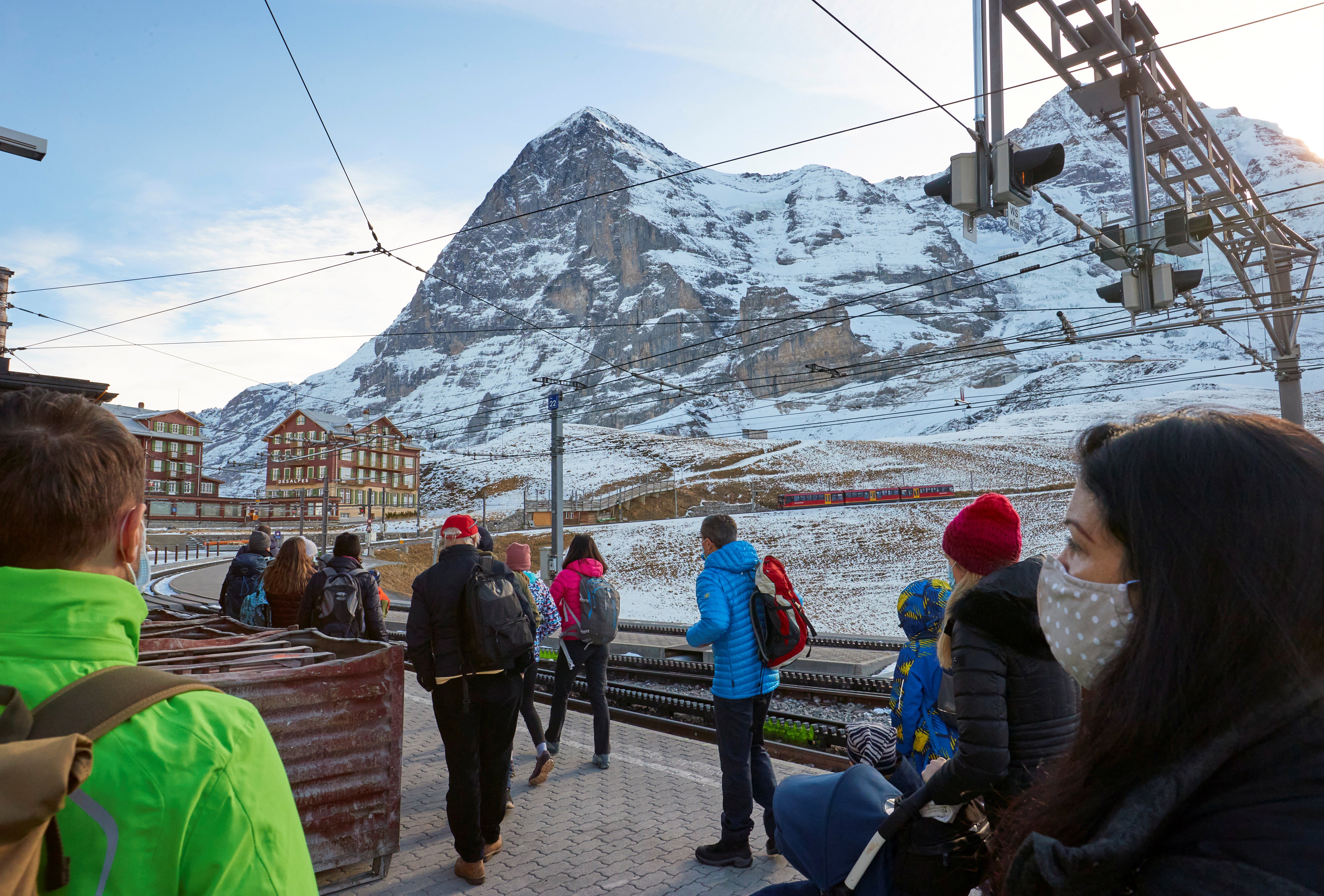 Passengers wearing protective masks wait to board the Jungfraujoch train in the ski resort of Grindelwald, Switzerland