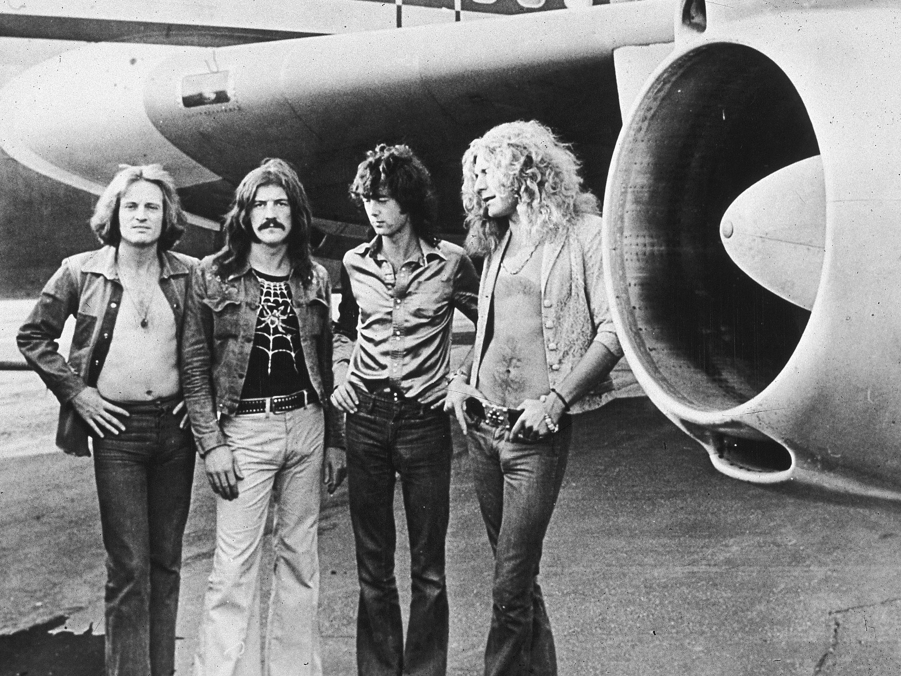 John Paul Jones, John Bonham (1948 to 1980), Jimmy Page and Robert Plant in front of their private airliner, The Starship, 1973