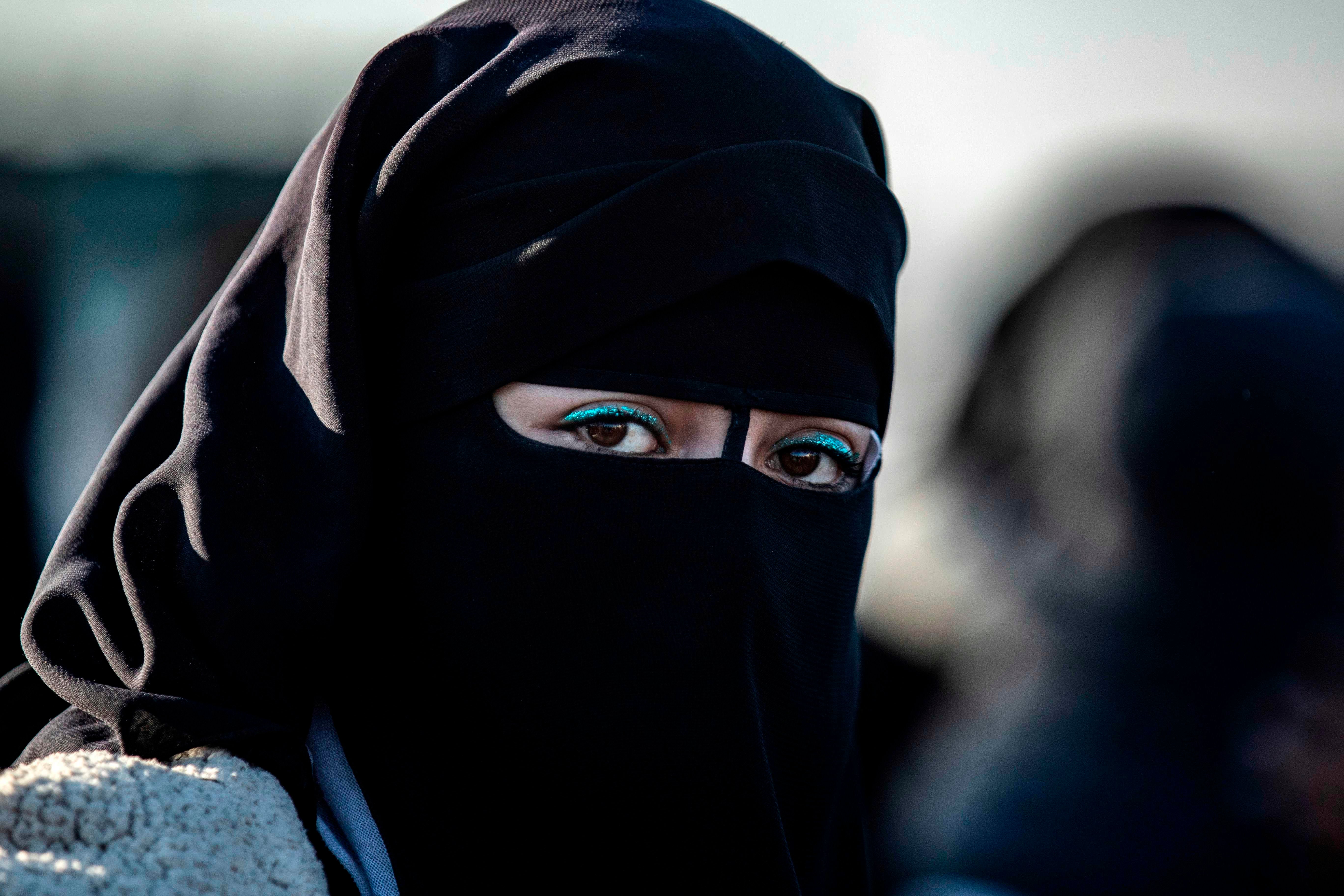 A Syrian woman waits to leave the Kurdish-run al-Hol camp holding relatives of alleged Islamic State group fighter