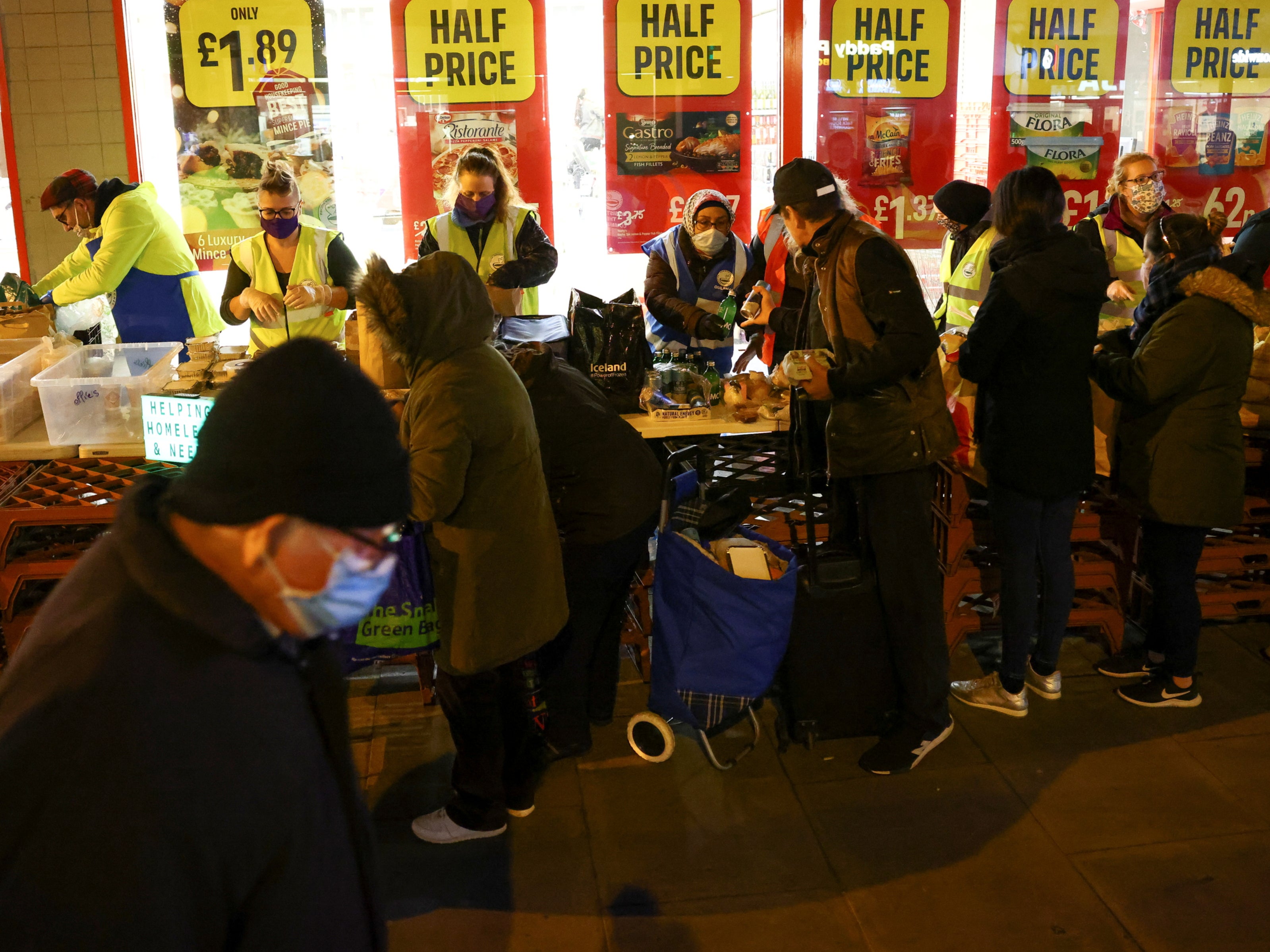 People queue to receive food donations from the Tooting Community Kitchen