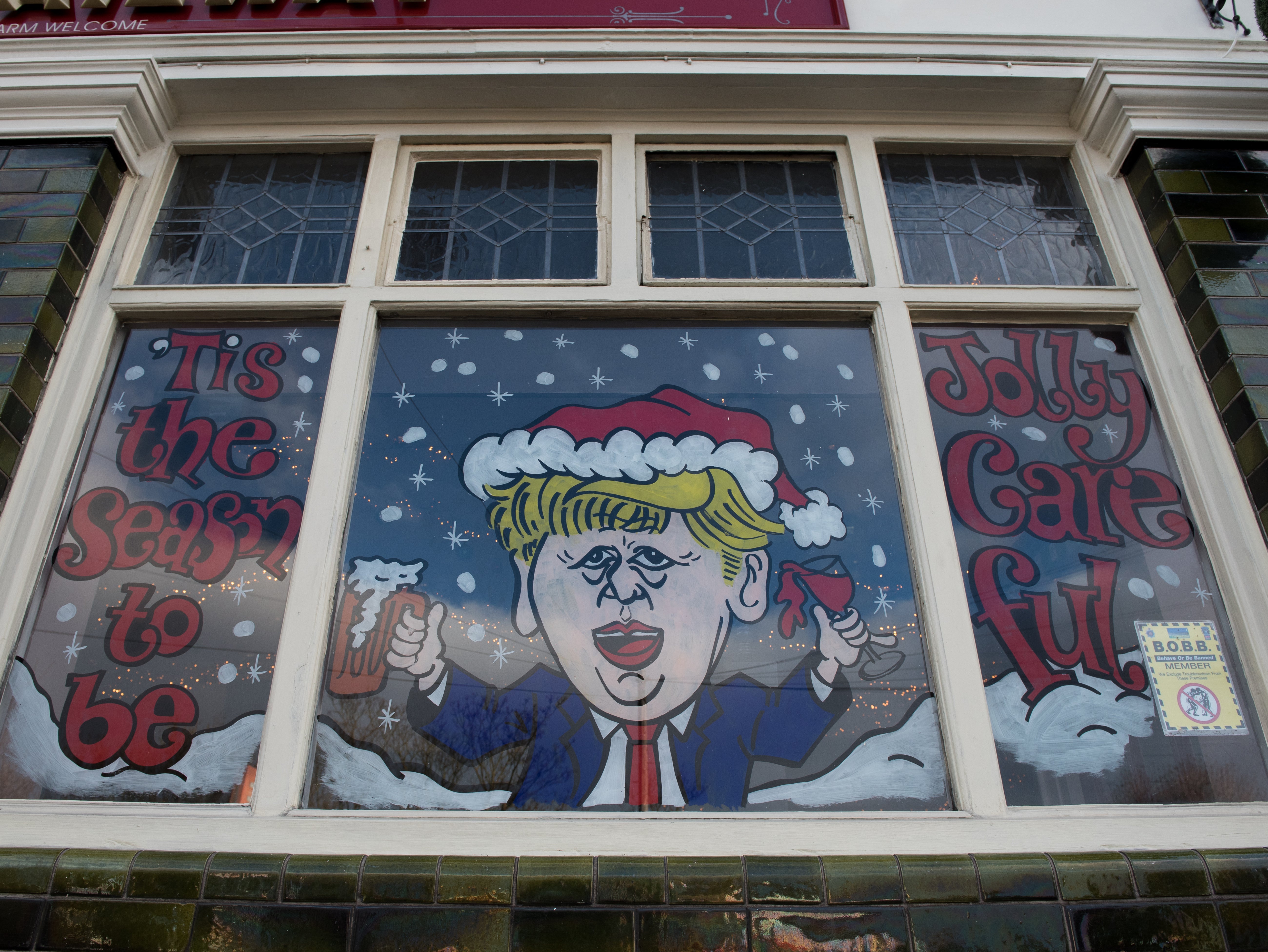 A humorous decorated window on The Railway pub showing a caricature of Boris Johnson and the words ‘Tis the season to be jolly careful’