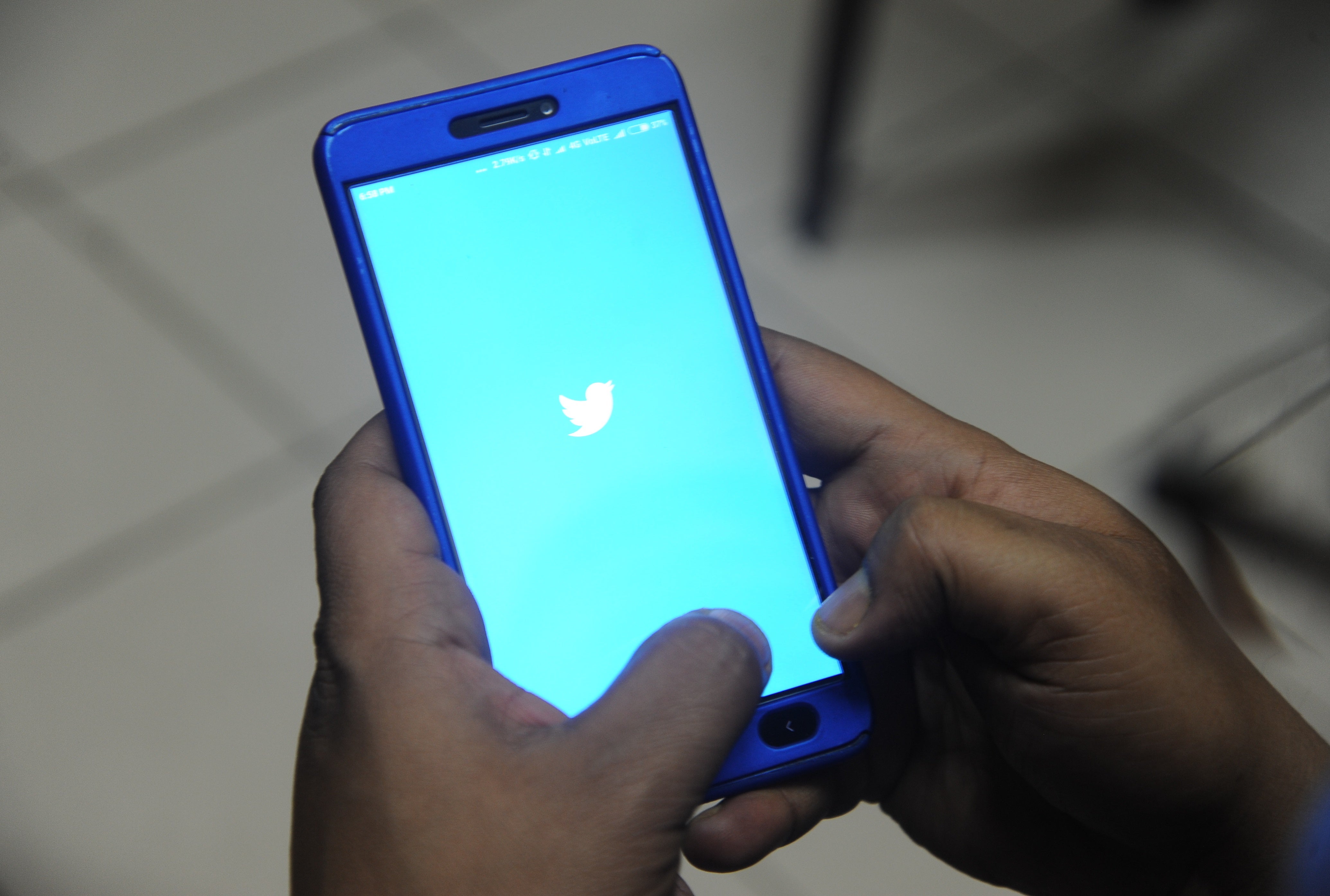 An Indian man poses for a photograph using Twitter on his cellpohne in Siliguri on March 27, 2018.