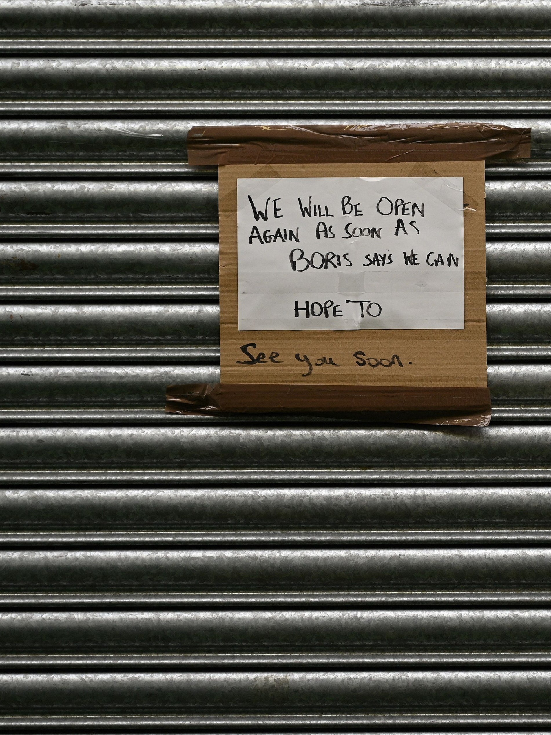 A sign on the shutters of a shop, closed due to the pandemic