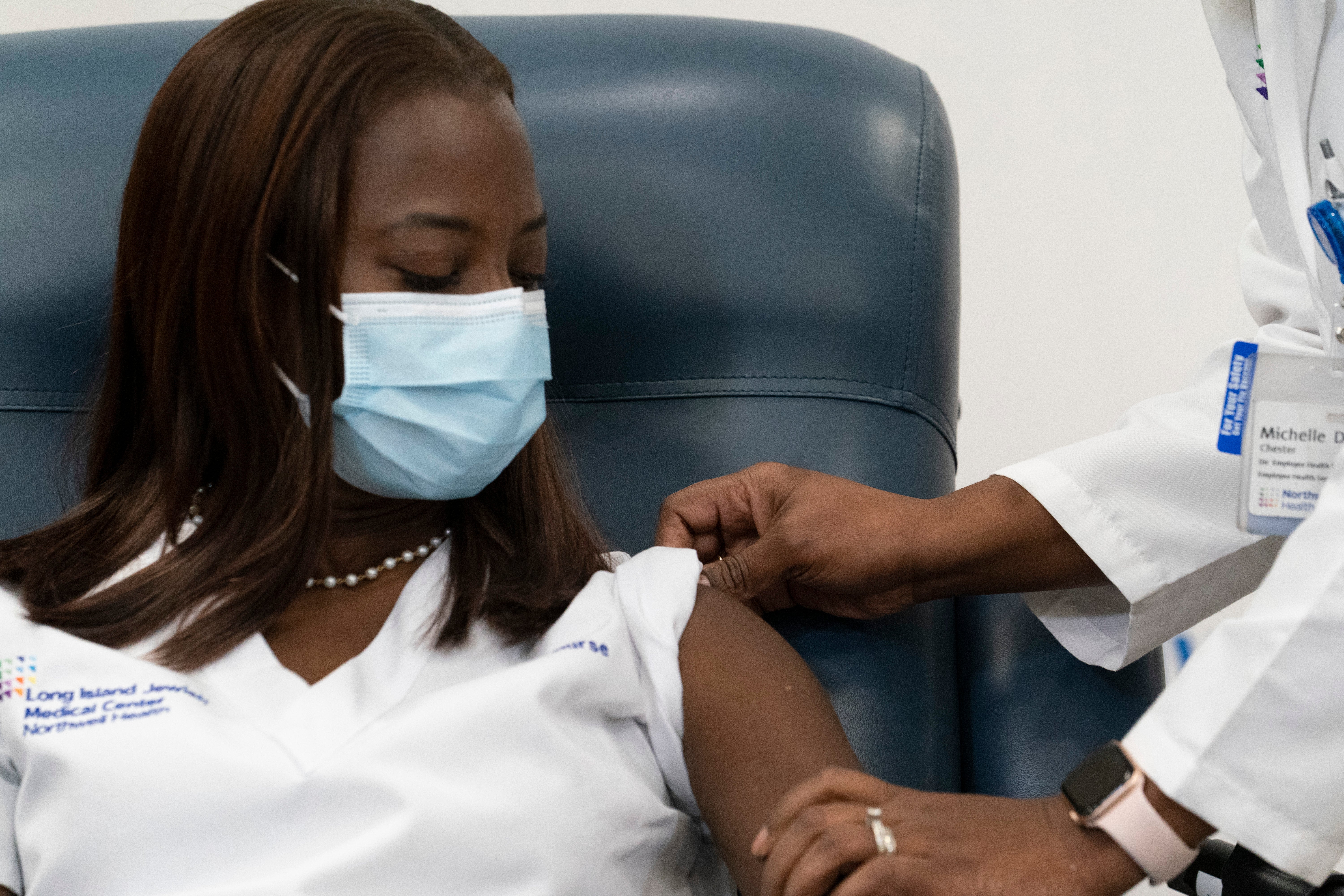 Dr. Michelle Chester, right, rolls up the sleeve of Sandra Lindsay, a nurse at Long Island Jewish Medical Center, before she is inoculated with the Pfizer-BioNTech COVID-19 vaccine, December 14, 2020 , at the Jewish Medical Center, in the Queens borough of New York City.