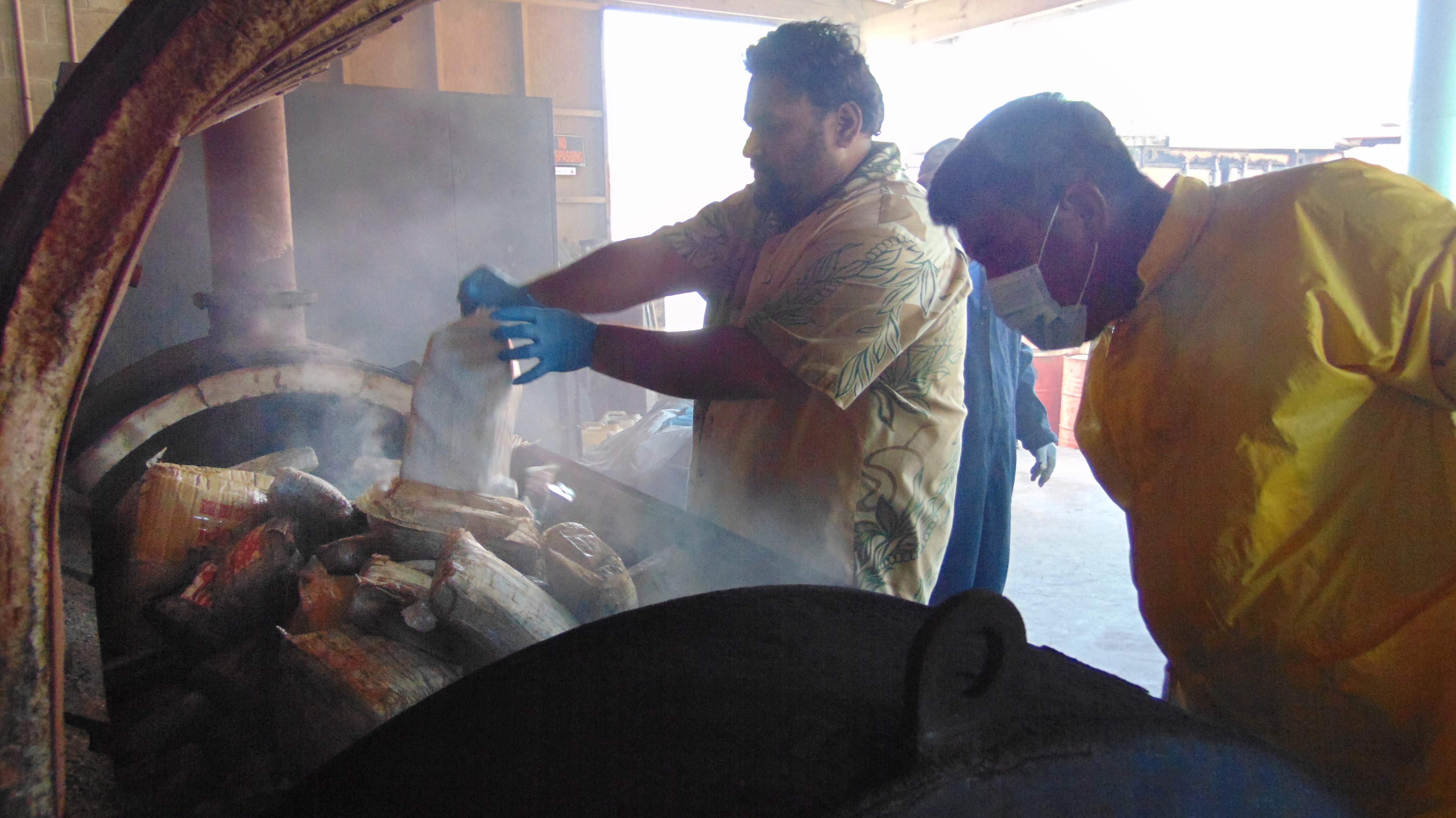 Marshall Islands Police Captain Eric Jorban, (L), emptying one-kilo packages of cocaine from the ghost boat into an incinerator in Majuro