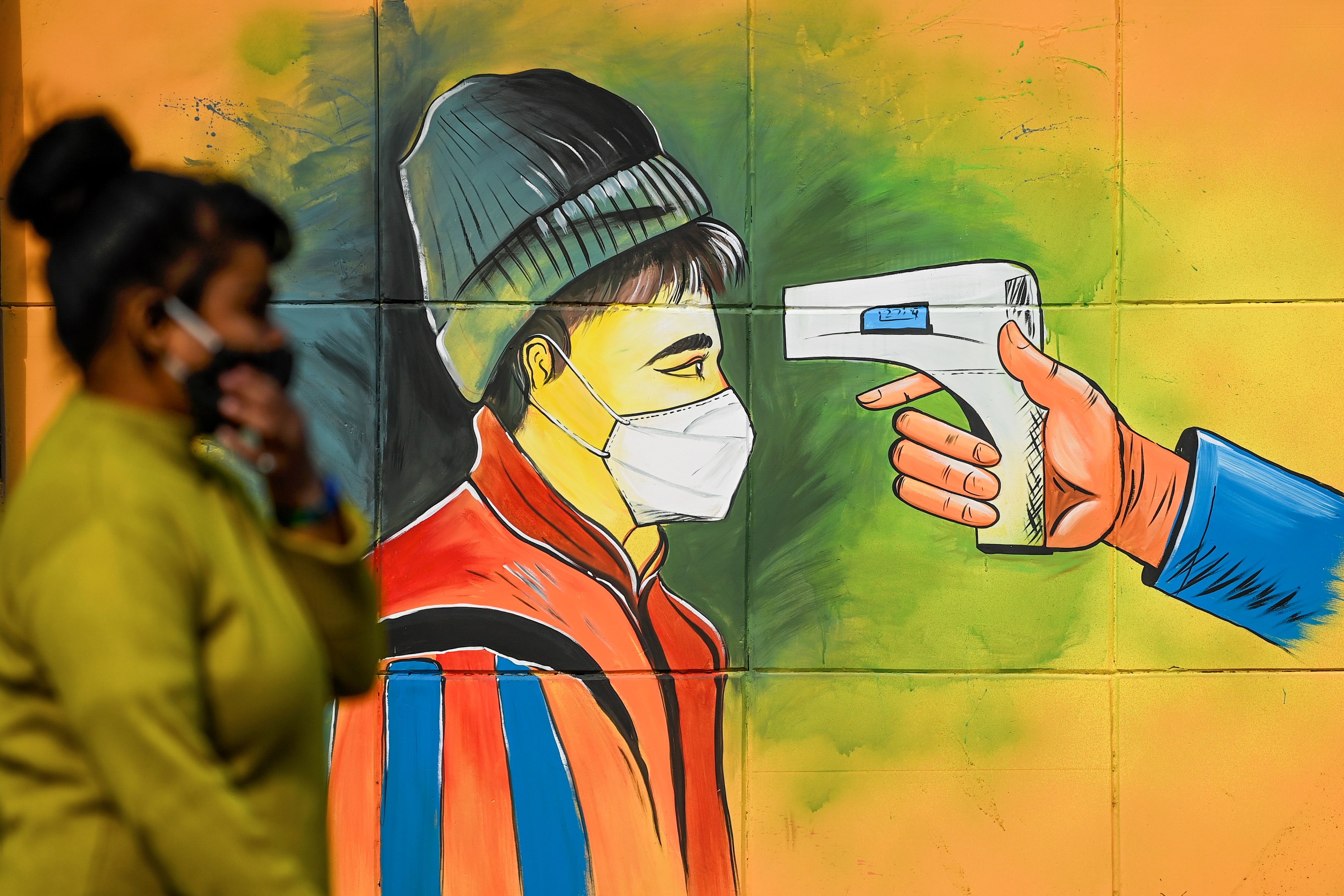 A woman walks past a mural in Delhi