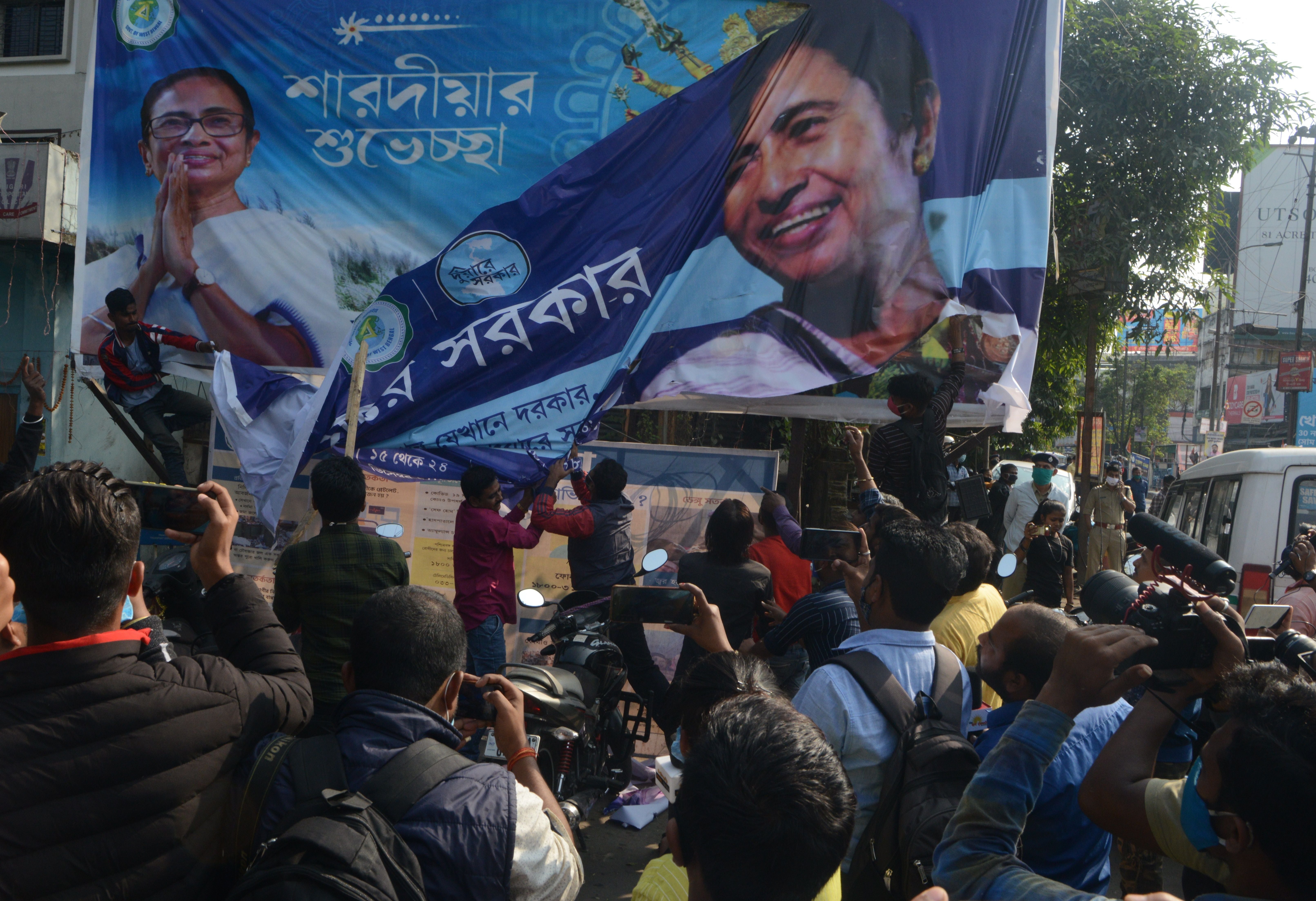 Bharatiya Janata Party supporters tear off a banner with a picture of West Bengal Chief Minister Mamata Banerjee Bharatiya Janata Party supporters block a road during a 12-hour general strike in North Bengal called by BJP to protest against the West Bengal state government in Siliguri on December 8, 2020