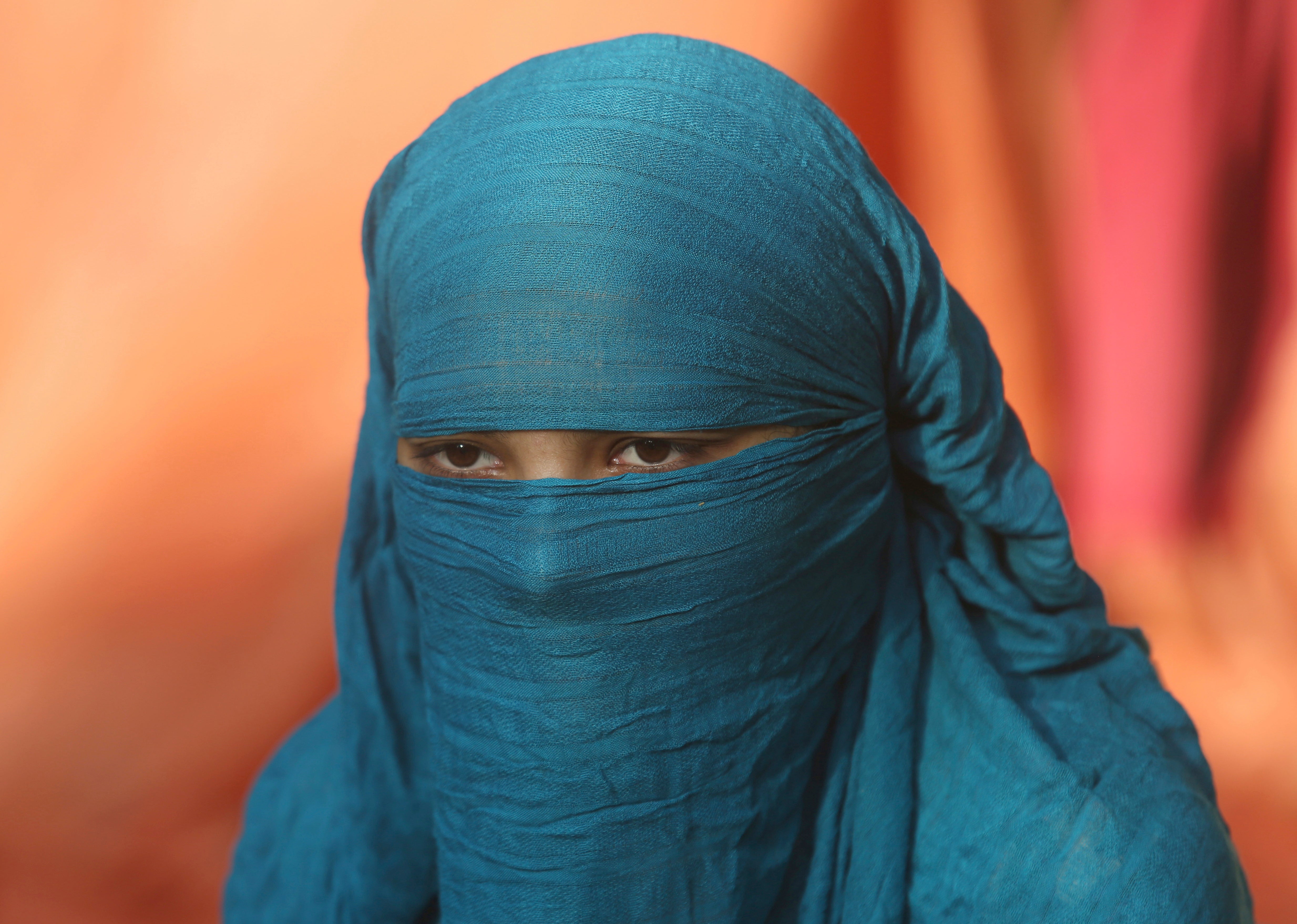 Fourteen-year-old Neha sits during an interview Wednesday Nov. 11, 2020, in Karachi, Pakistan. Neha's family forced her to marry a 45-year-old Muslim man, who first made her convert from Christianity to Islam. She's among hundreds of Christian and Hindu girls from poor families who are forced to convert each year, usually ahead of being married off to older Muslim men. Activists say the practice has accelerated during lockdowns against the coronavirus, when girls are out of school and more visible, bride traffickers are more active on the Internet and families are more in debt. (AP Photo/Fareed Khan)