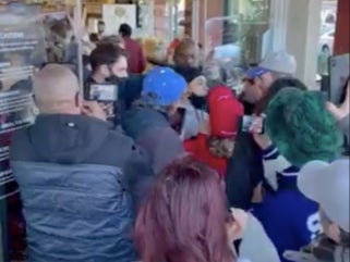 A video captured by a bystander shows a crowd of maskless people pushing to get into a store