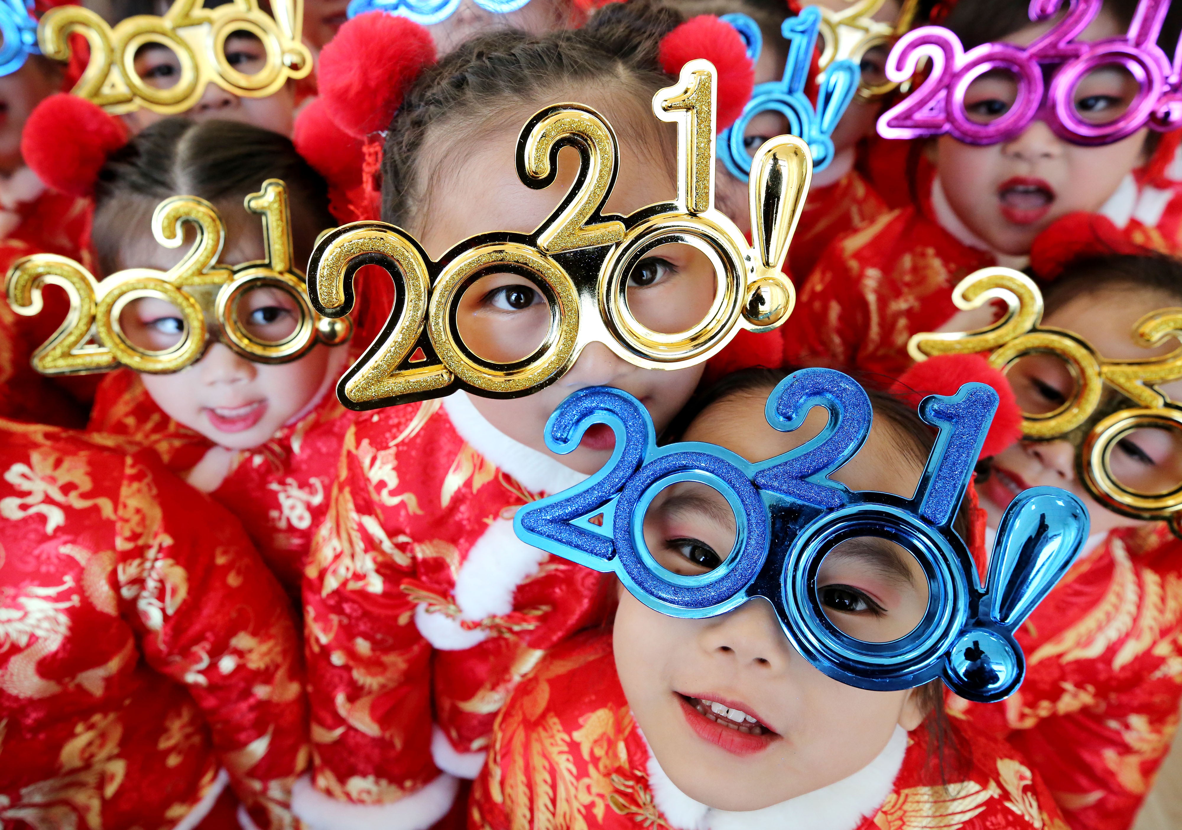 Children wearing glasses featuring number ‘2021’ pose for a photo to welcome the New Year in Zaozhuang, Shandong Province of China