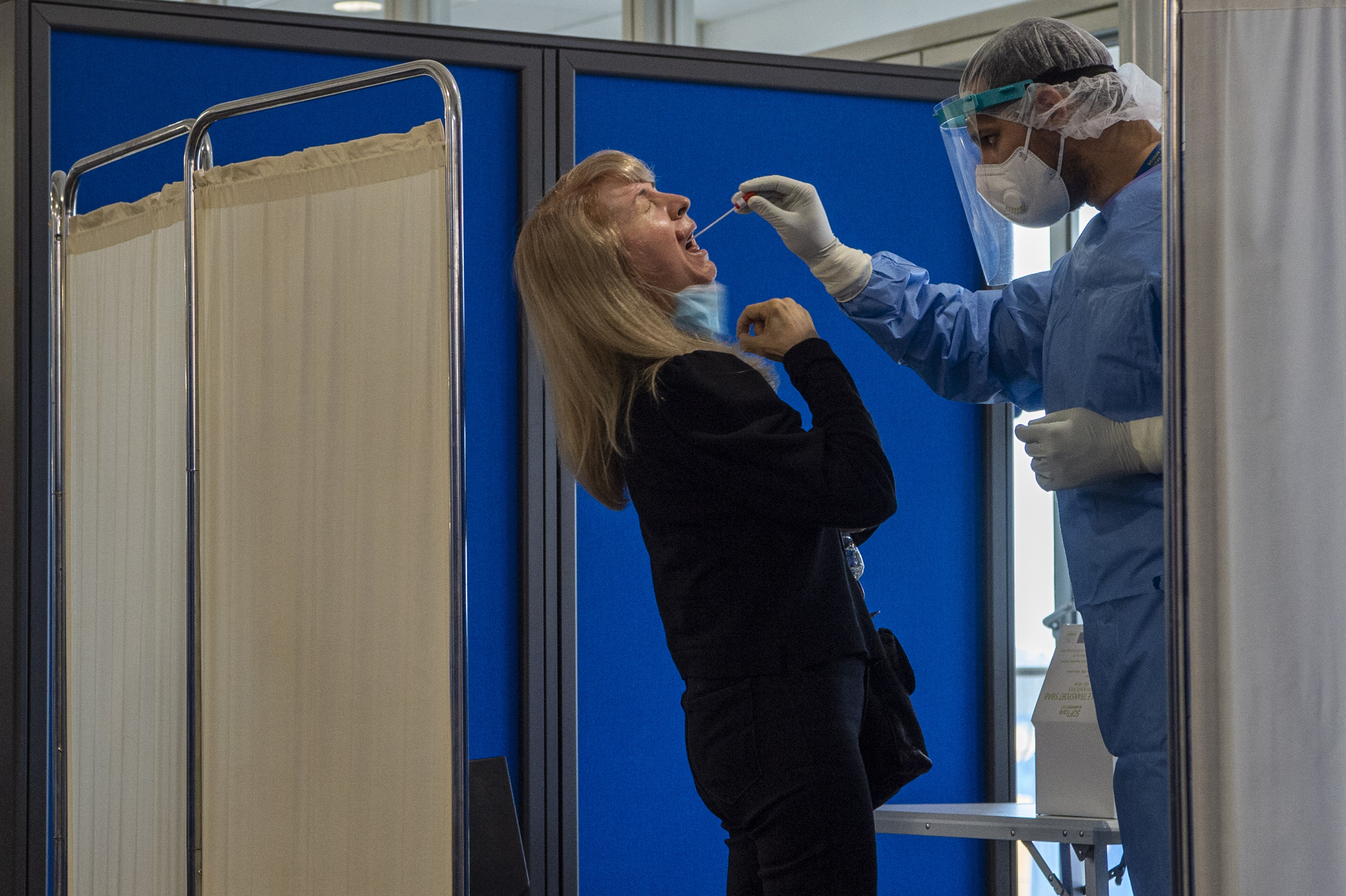 Medical staff conduct a test for the new coronavirus on passengers at Athens airport in June