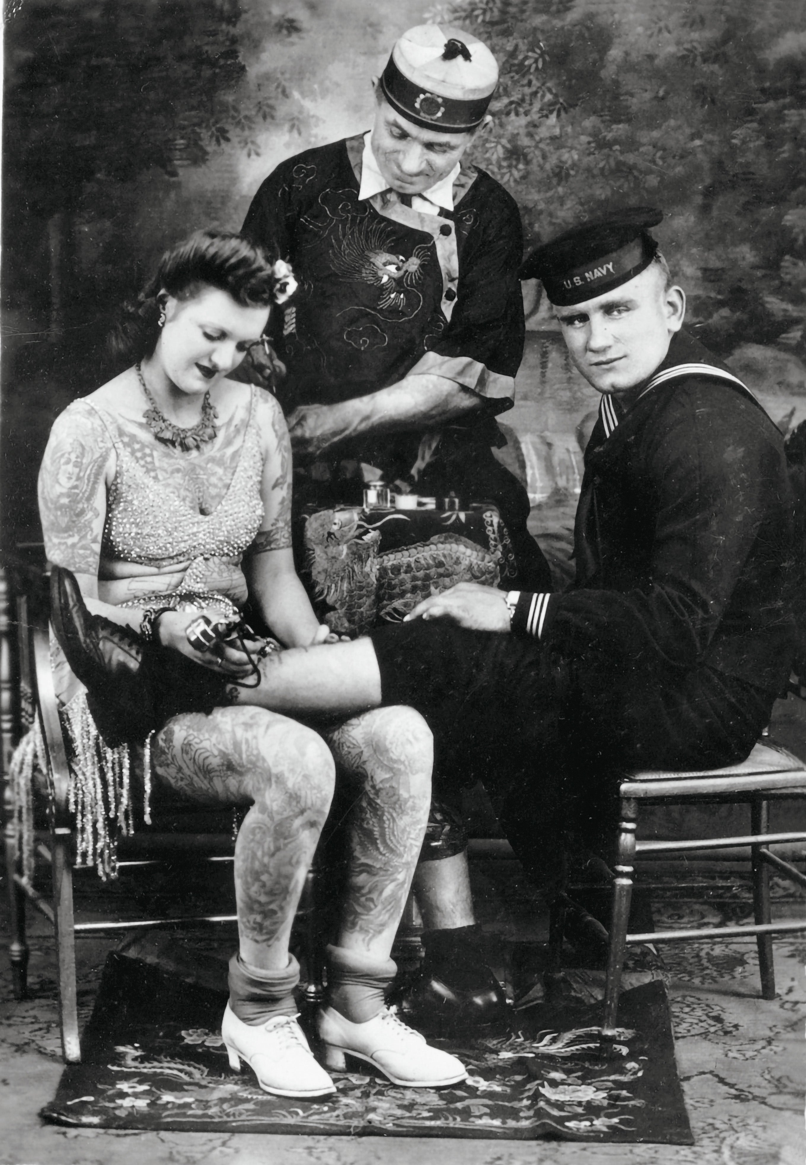 Famous American tattoo artist Charlie Wagner, center, with a tattooed lady and American sailor, ca. 1930s. Wagner loved staging photographs. Here, he’s tattooing the tattooed lady’s shoulder, while she tattoos the young sailor.